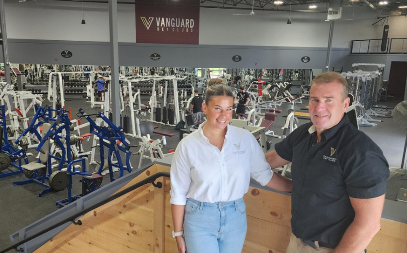 Two Vanguard Key Clubs staff members standing on an upper level overlooking a fully equipped gym floor.