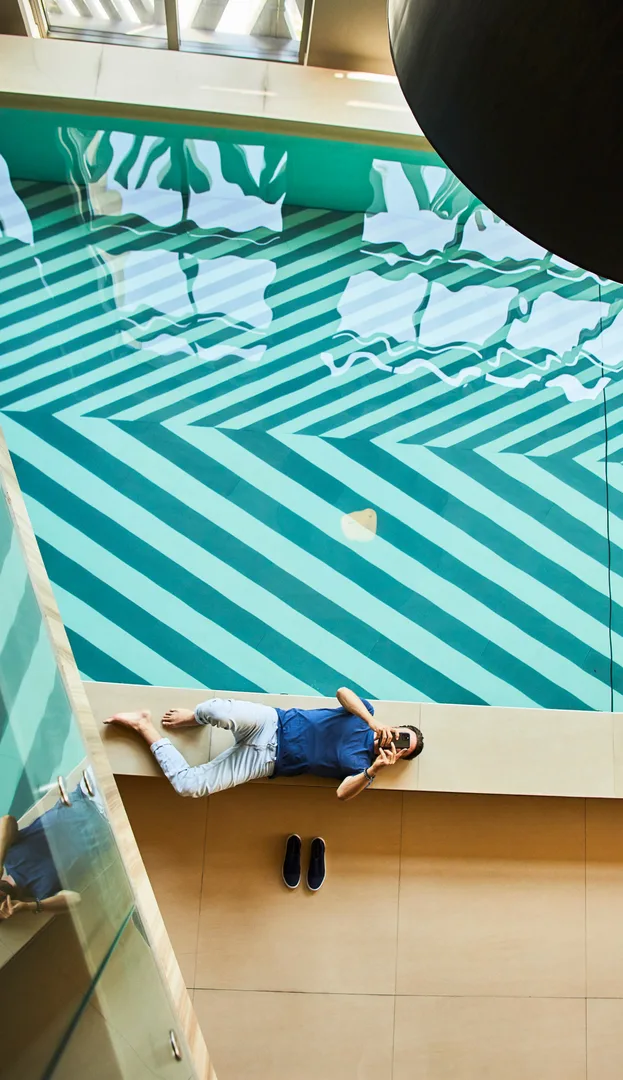 Homem relaxando na beirada de uma piscina luxuosa