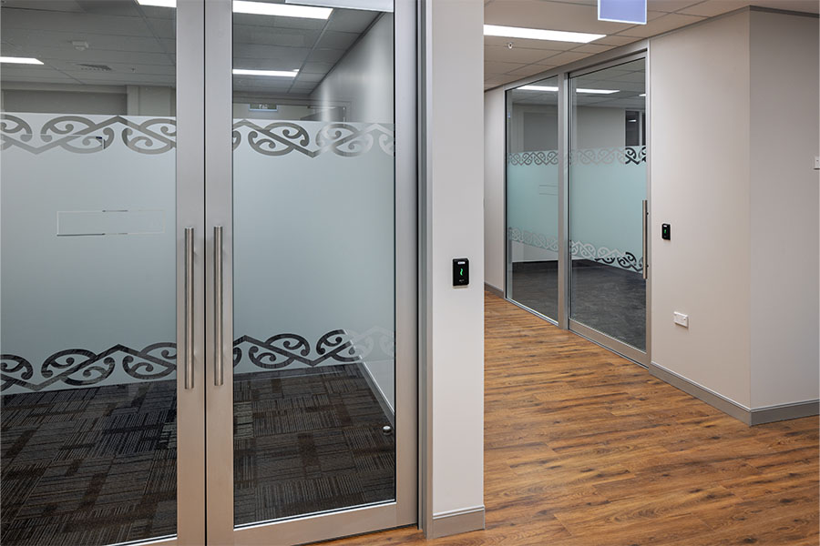 Glass-walled meeting rooms with wooden flooring in office interior