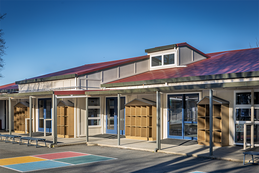 Exterior view of new school building featuring timber cladding, pitched roof, and covered entryway.