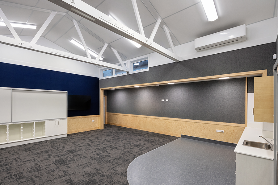 Open-plan teaching space with acoustic wall panels, built-in shelving, and durable finishes for education use.