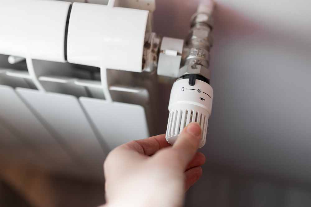 Image shows a close up of someone adjusting a radiator valve