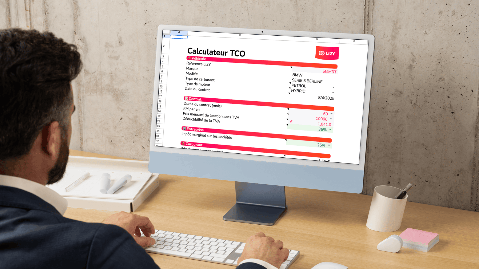Man in a suit using a desktop computer showing a French Total Cost of Ownership calculator for a BMW Series 5 hybrid car.