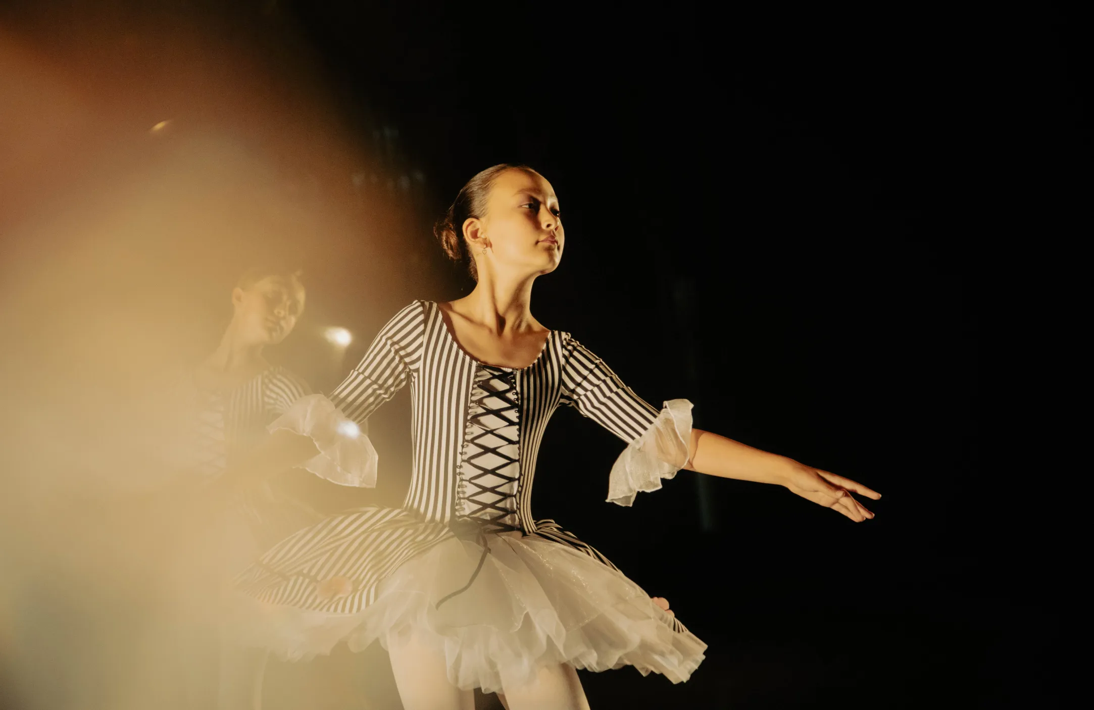A woman in a striped dress is dancing in front of a blurry background.