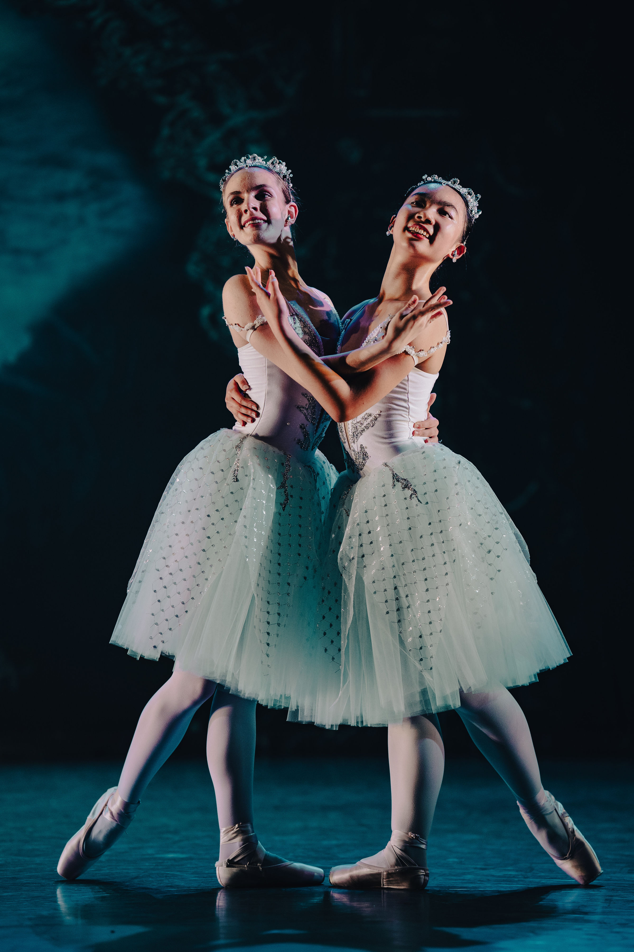 Two female ballet soloists en pointe in white costumes and tiaras performing onstage at The Russian Ballet School showcase in Toronto