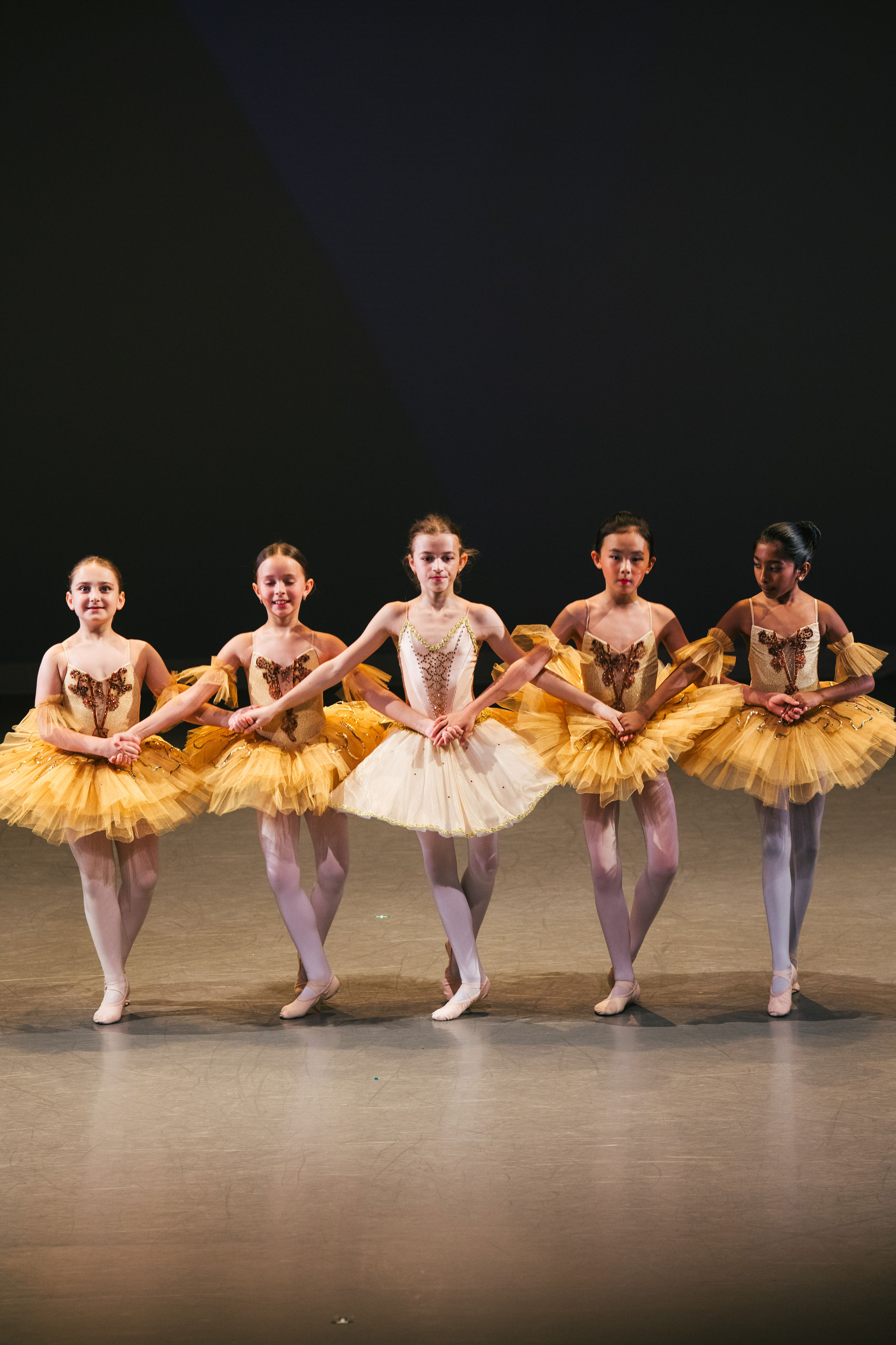 Students of the Russian Ballet School dancing on stage in yellow costumes.