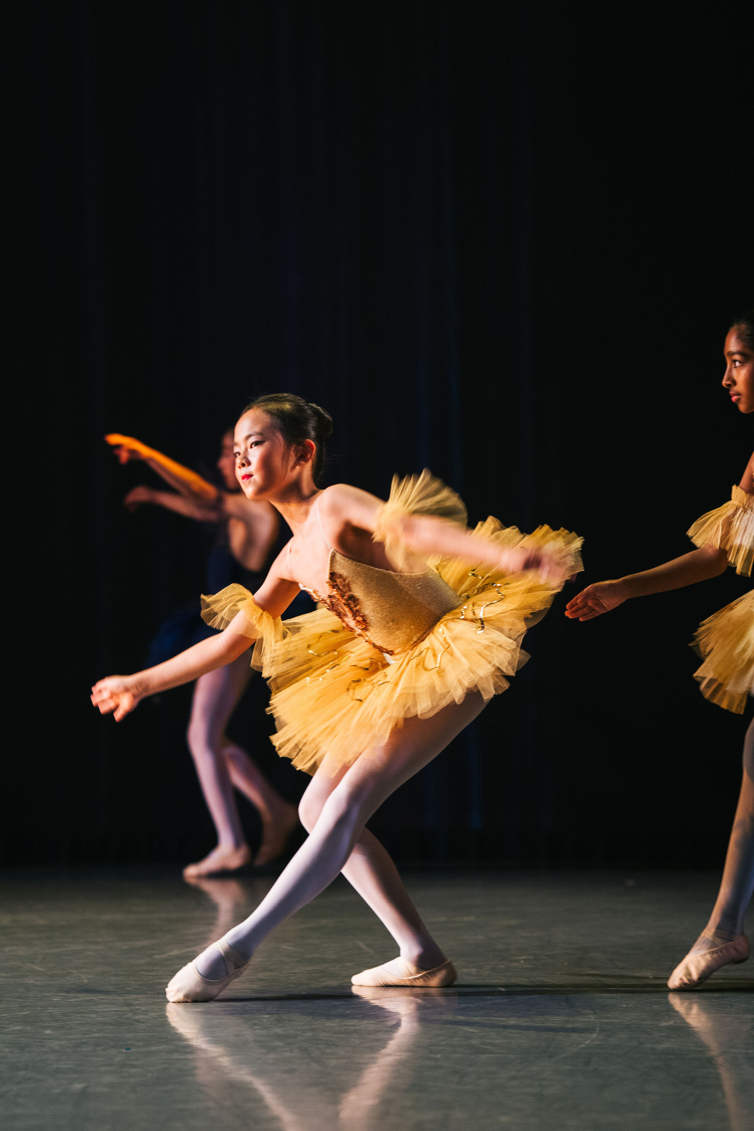 Asian student in yellow dress performing at the annual showcase produced by The Russian Ballet School.