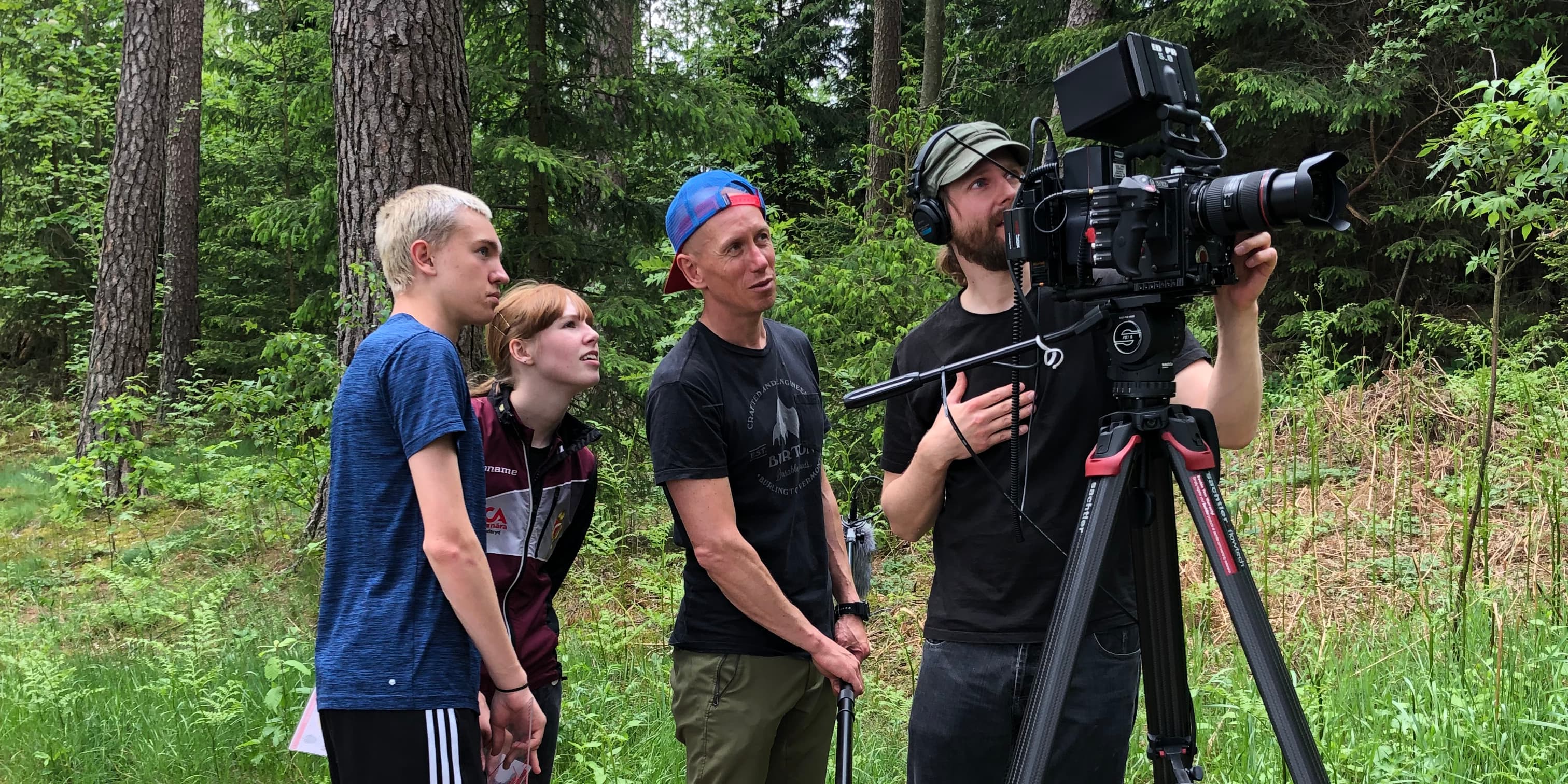 Filmteam framför kameran under en inspelning i skogen
