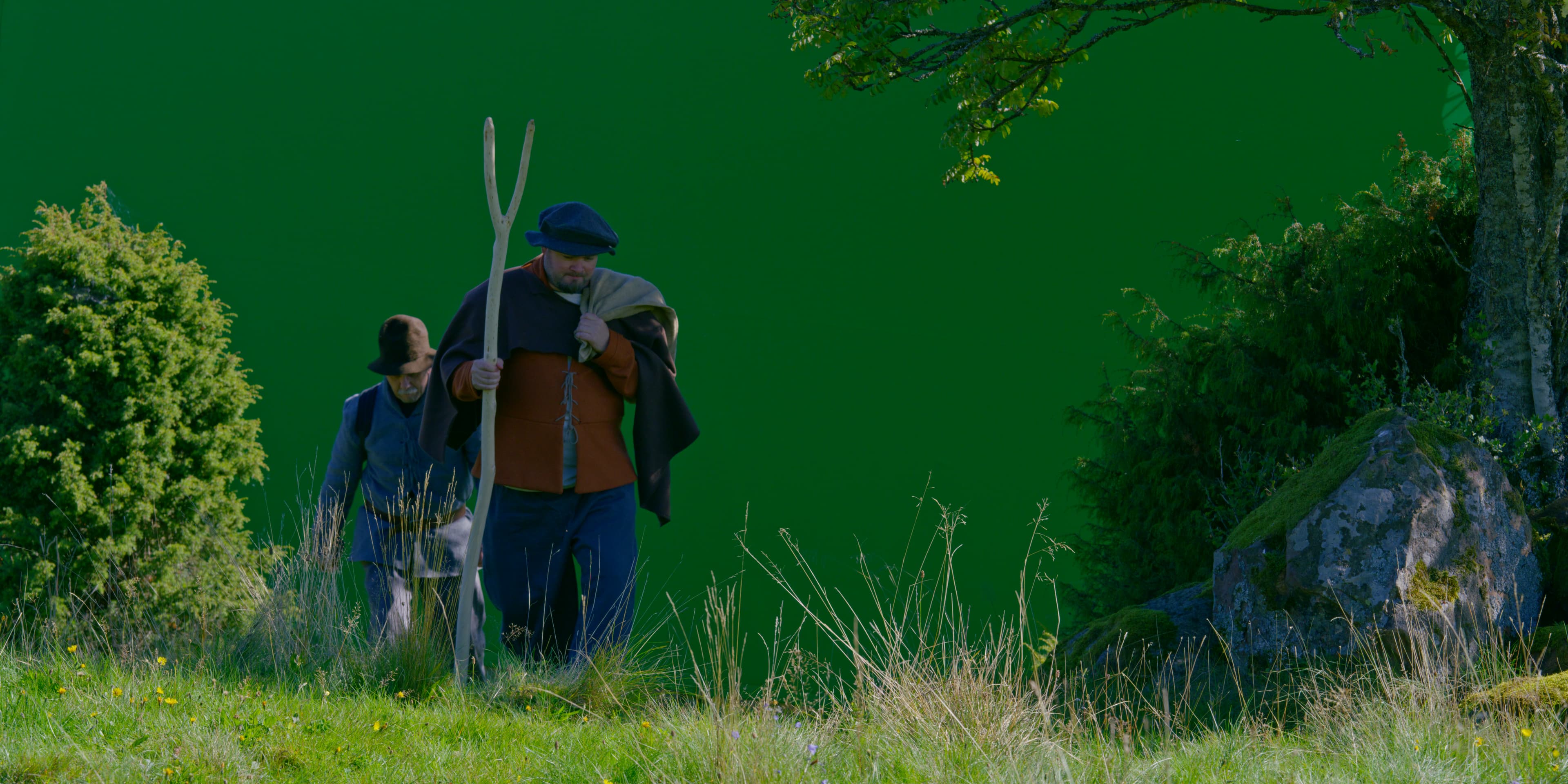 Två personer i historiska kläder framför greenscreen i en utomhusmiljö
