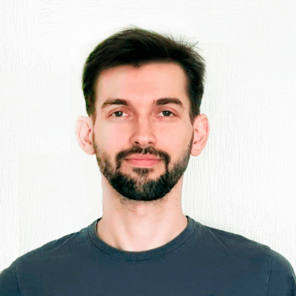 Bearded man in a dark T-shirt against a white wall