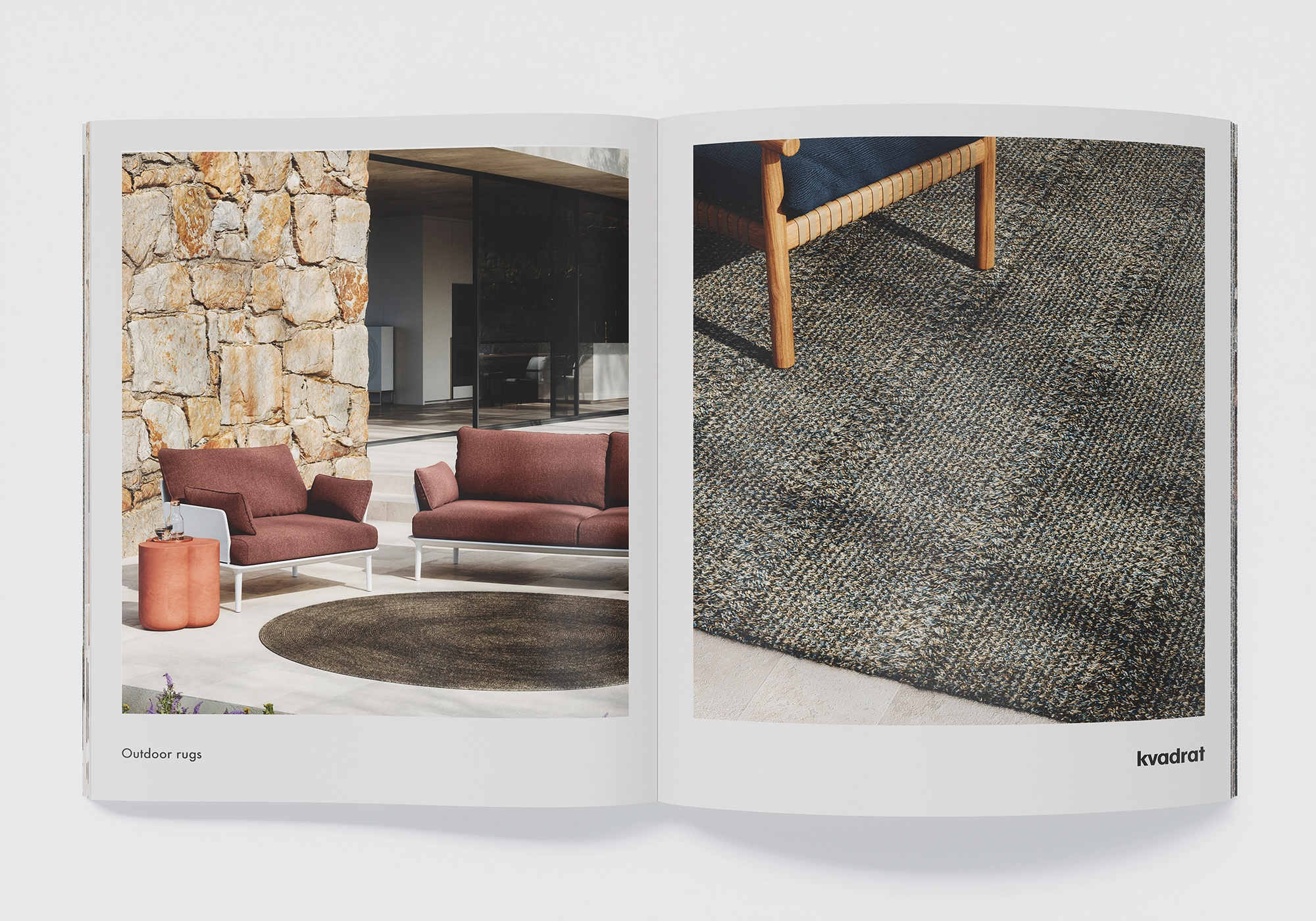 Outdoor-Lounge mit rundem Kvadrat-Teppich vor Natursteinwand; zwei Sofas, Beistelltisch und mediterrane Terrasse – fotorealistisches 3D Rendering.