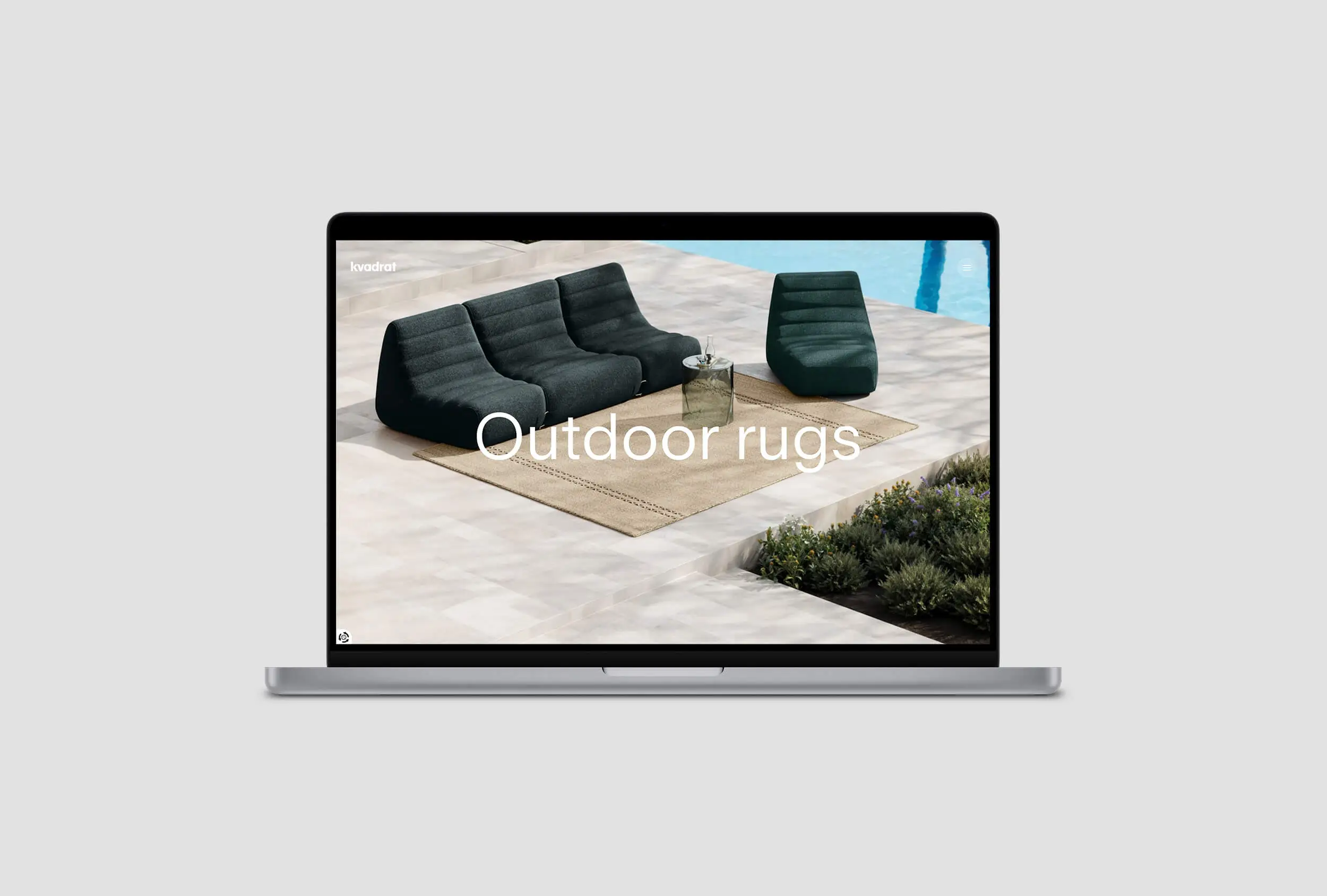 Il laptop mostra il sito web di Kvadrat con l'immagine hero della collezione "Outdoor Rugs", visualizzata in una scena mediterranea con piscina.