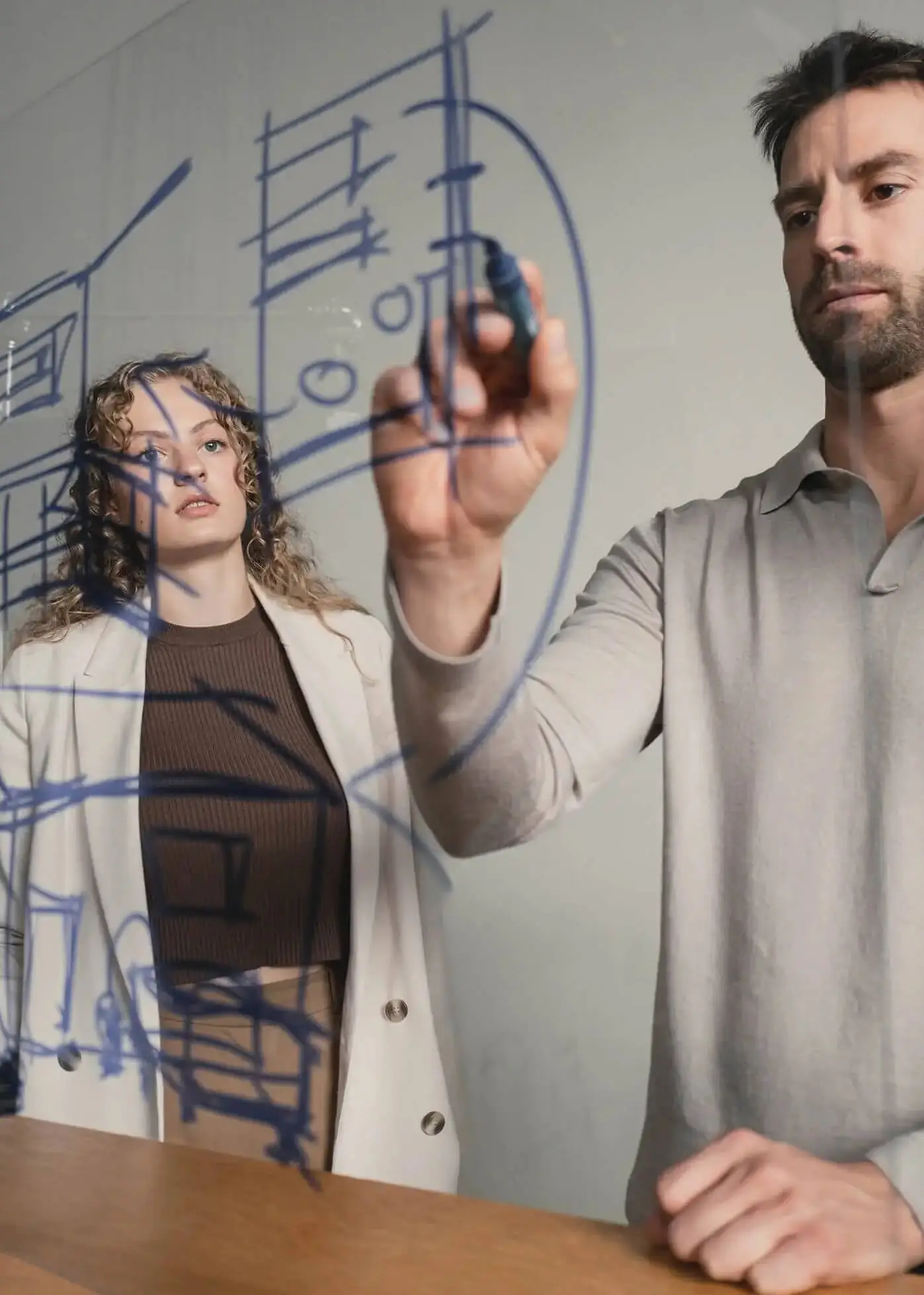 Danthree Studio team brainstorming a visual brand strategy and sketching concepts on a glass board.