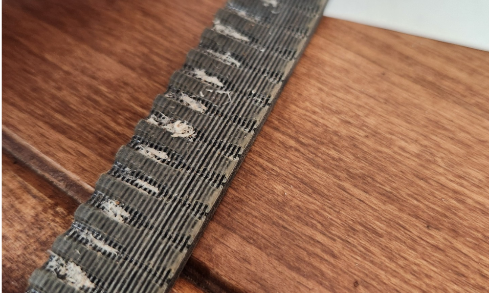 Image of a timing belt with visible uneven tooth wear. 