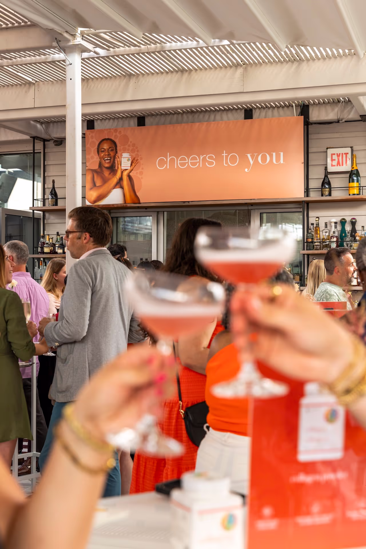 A crowded event with a "cheers to you" sign