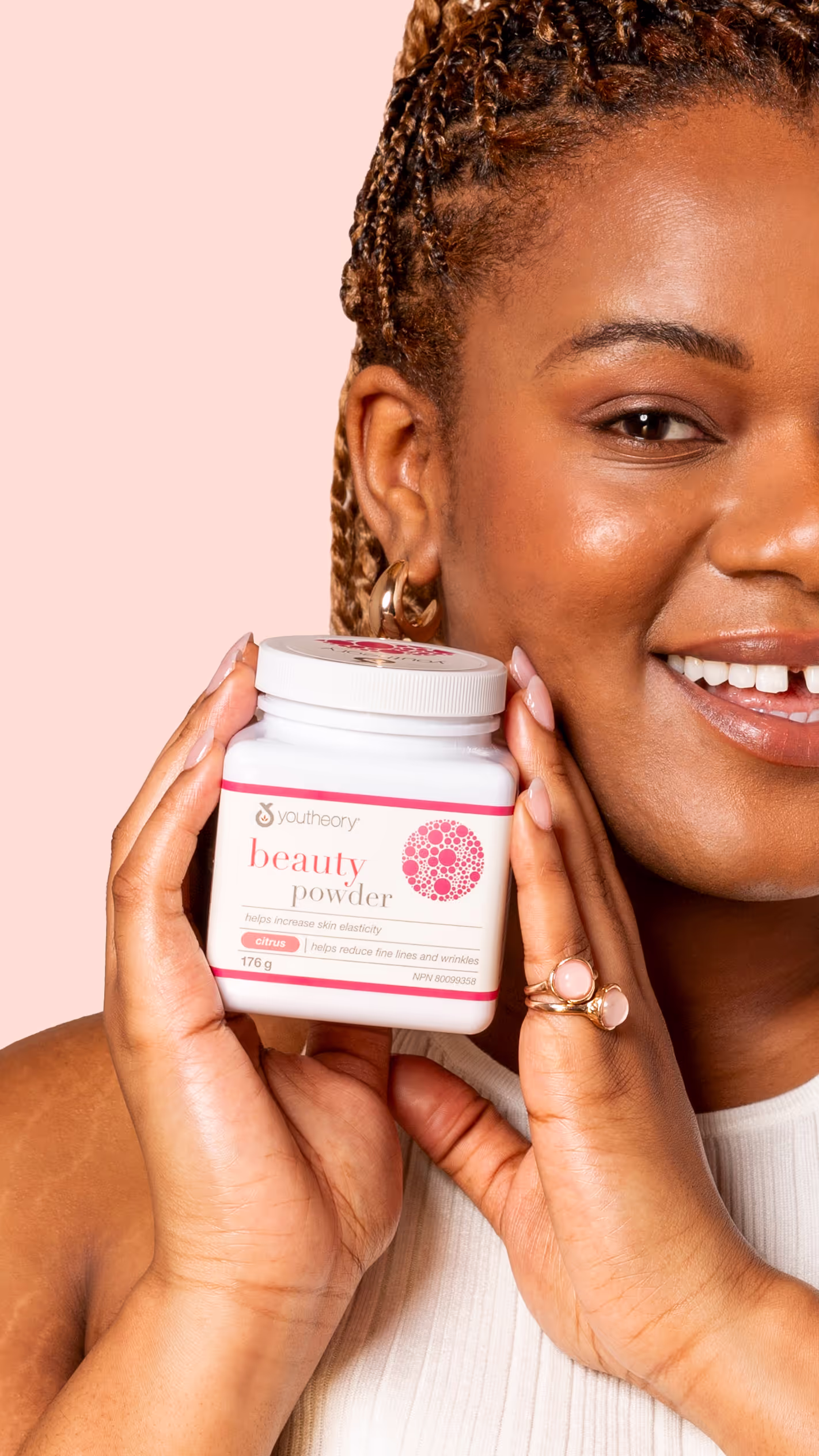 Smiling woman holding a container of YouTheory beauty powder with citrus for skin elasticity and wrinkle reduction.