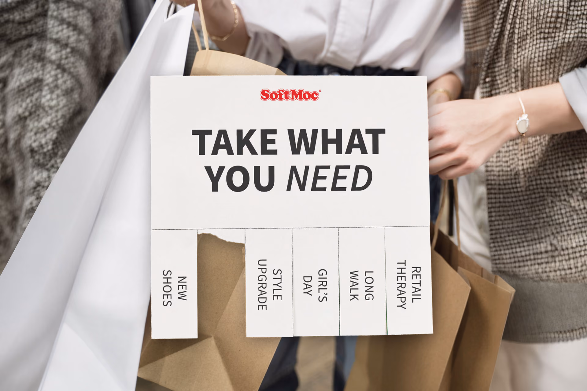Hands holding a tear-off flyer saying Take What You Need with options like New Shoes and Retail Therapy.
