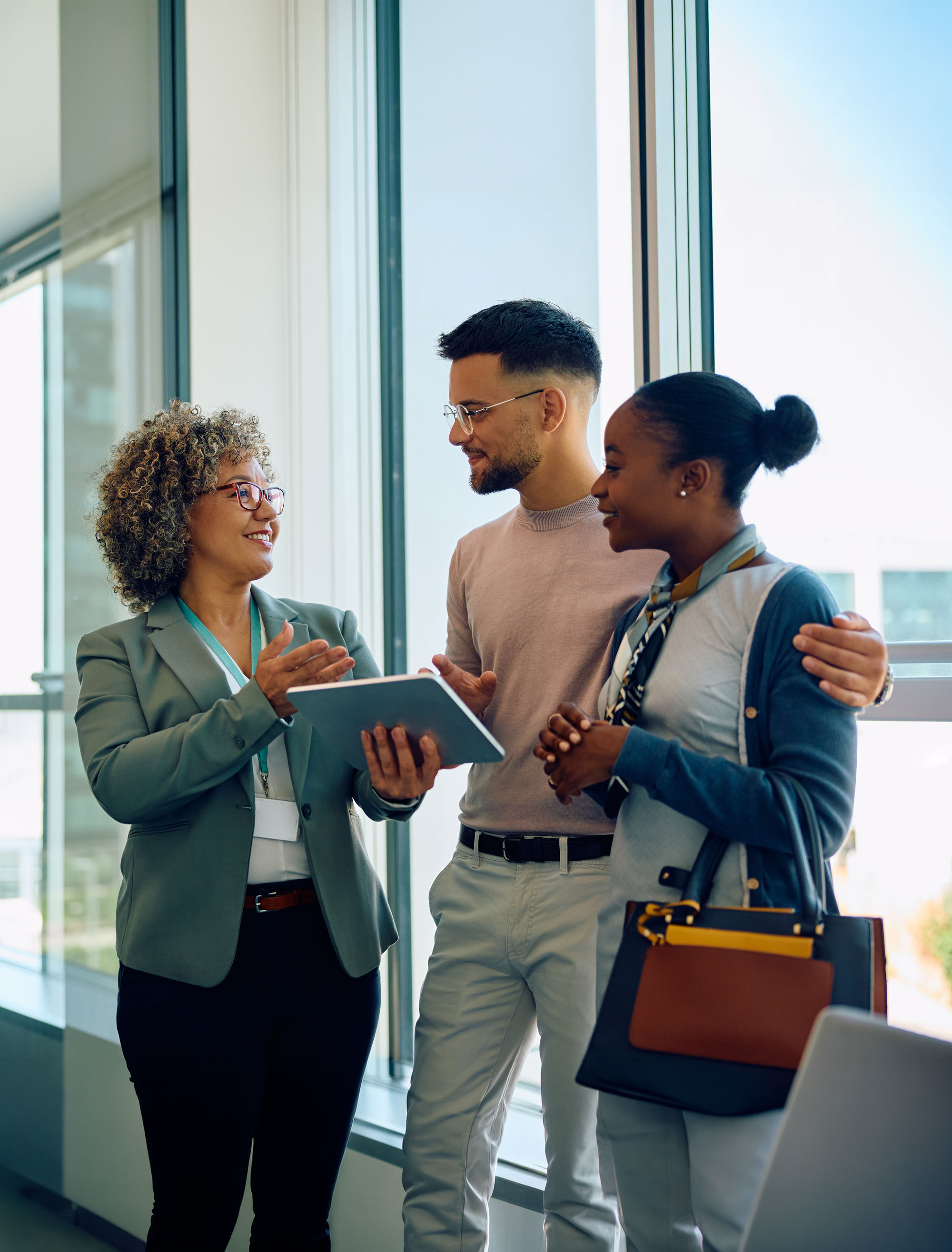A financial advisor showing a tablet to two clients in a bright office