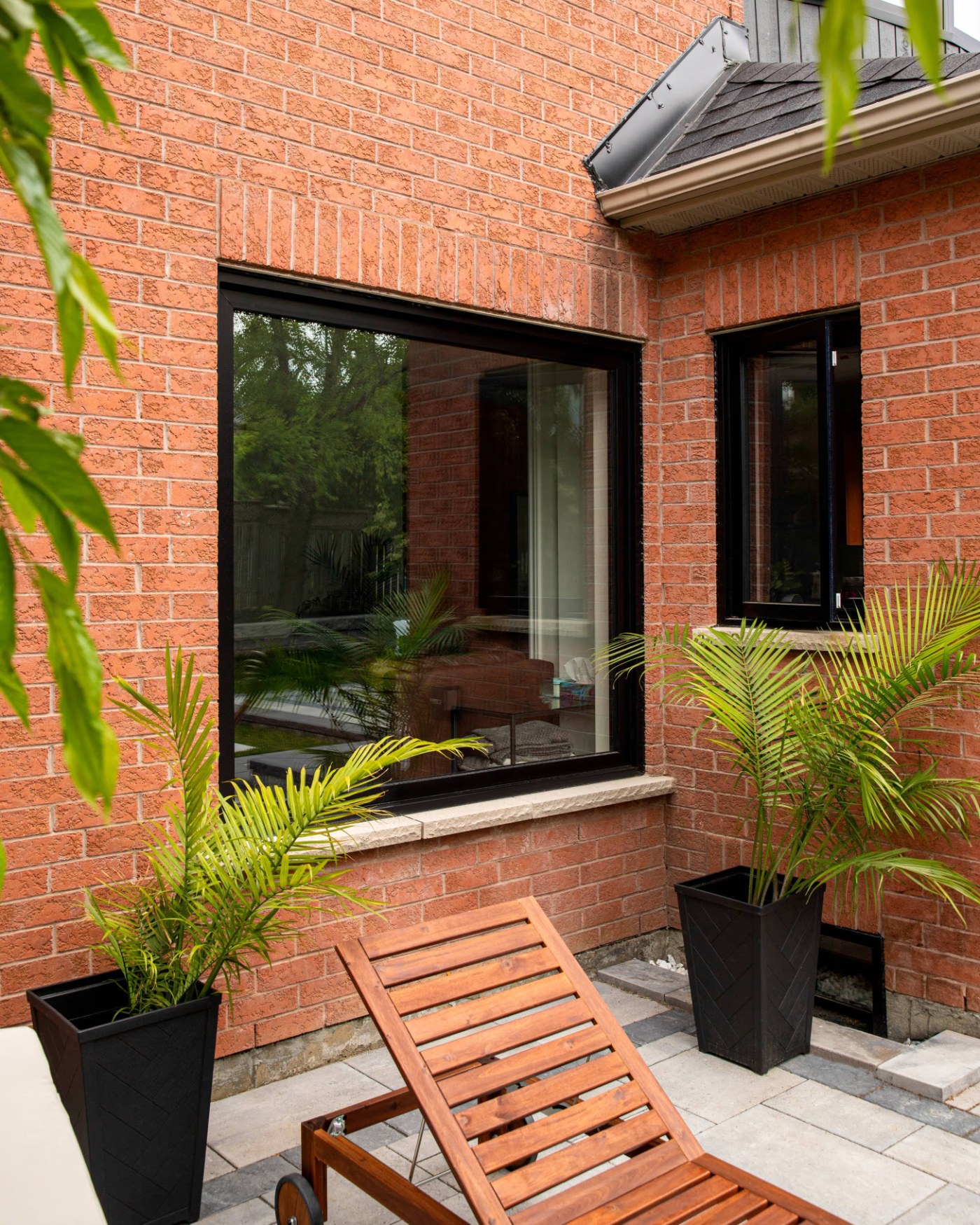 Black-framed Clera window on a brick wall above a patio