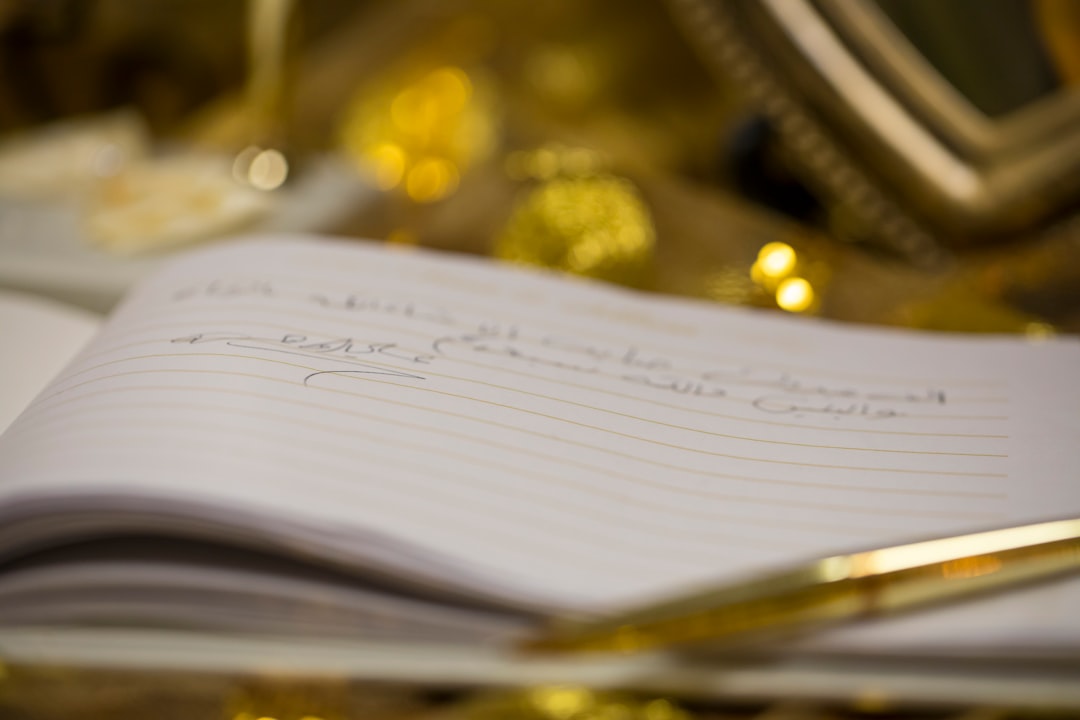 A golden pen rests on a notebook with writing.