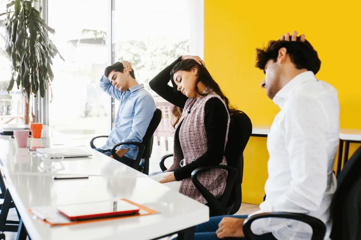 Work colleagues doing neck stretches at their desk