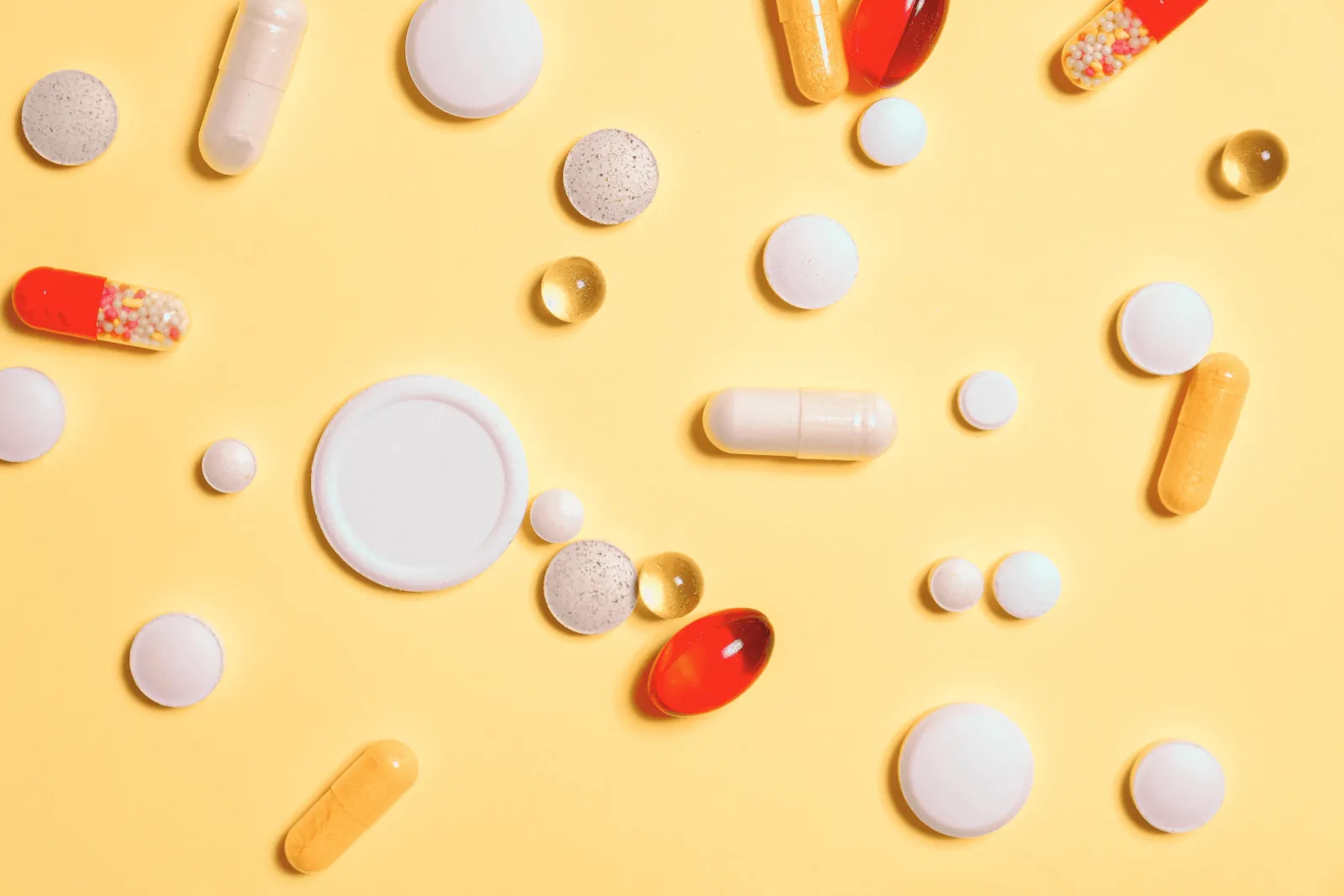 Medication pills spread on a yellow surface