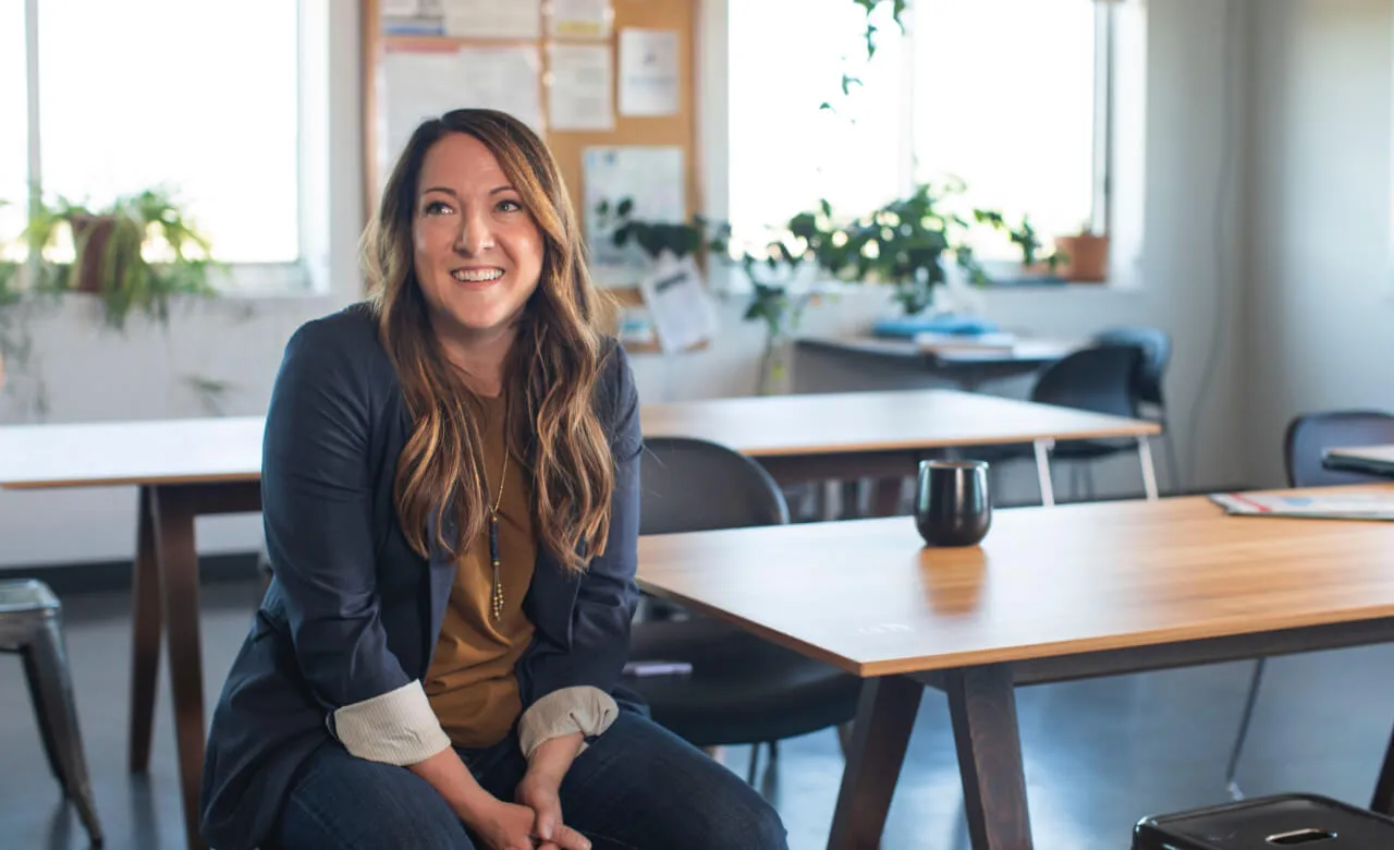 Woman smiling sitting next to a desk