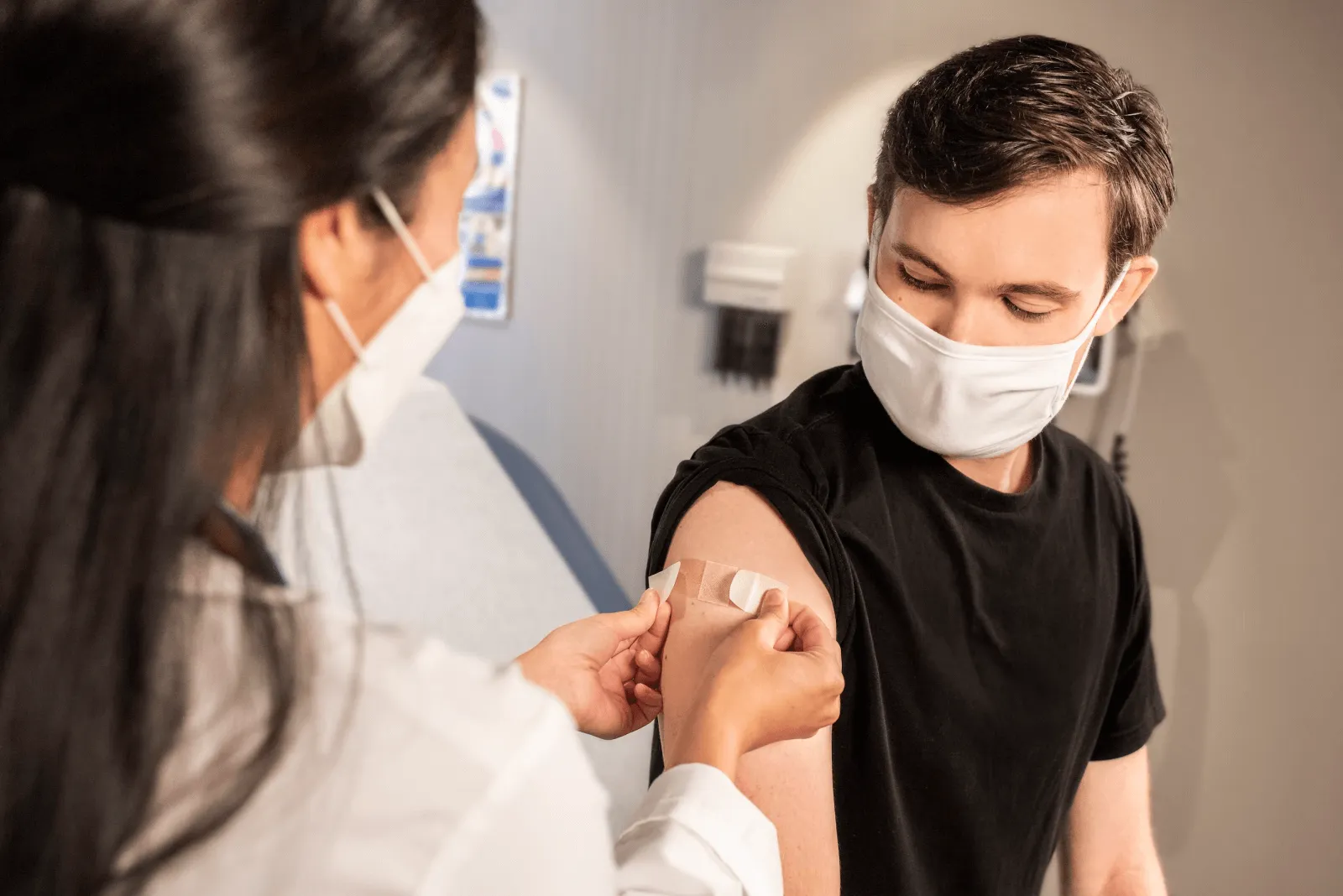 Doctor putting a bandaid on a patient's arm after an injection
