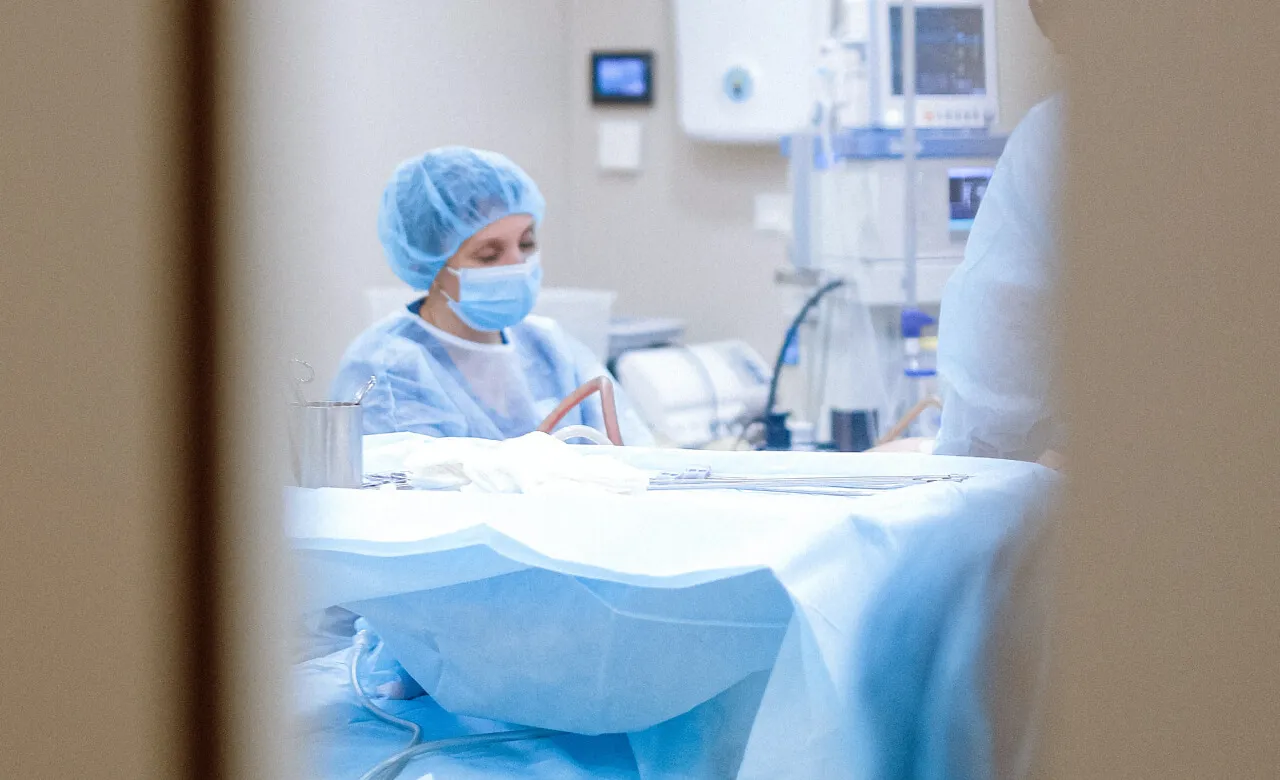 Window into surgery theatre with a surgeon working on a patient
