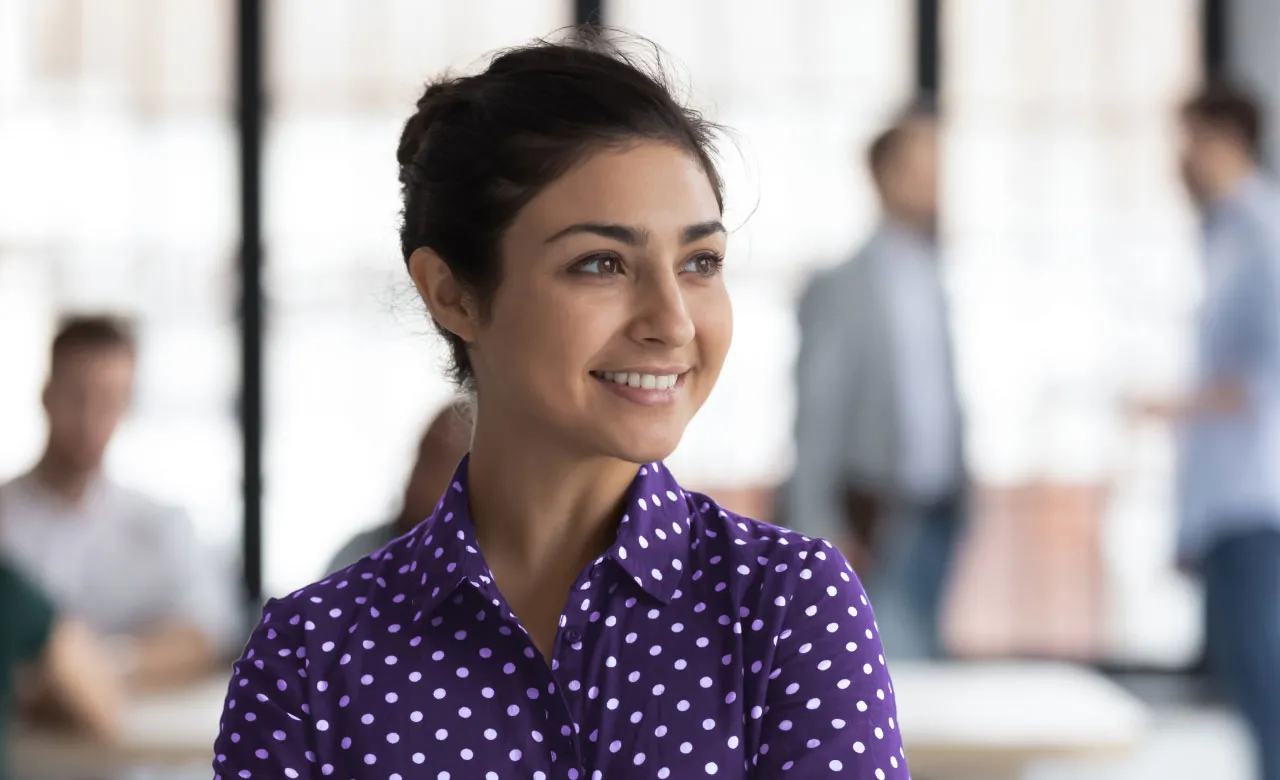 Woman in an office setting smiling and looking to the right