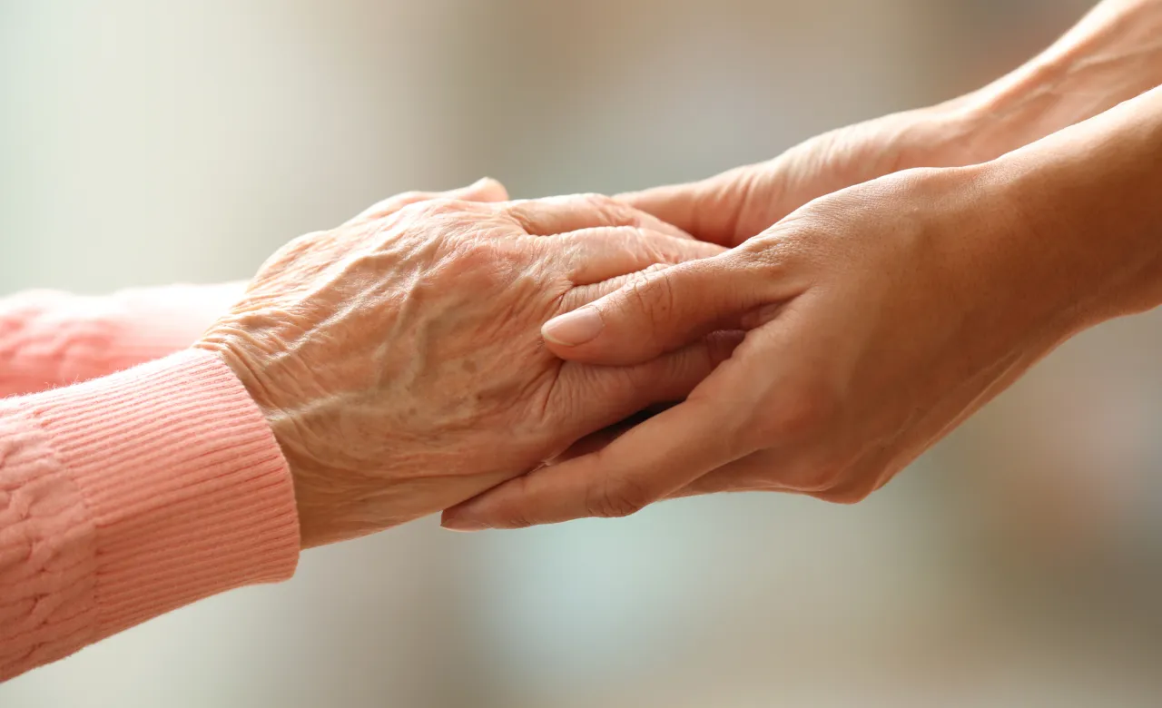 Older person's hands being held by a younger person's hands