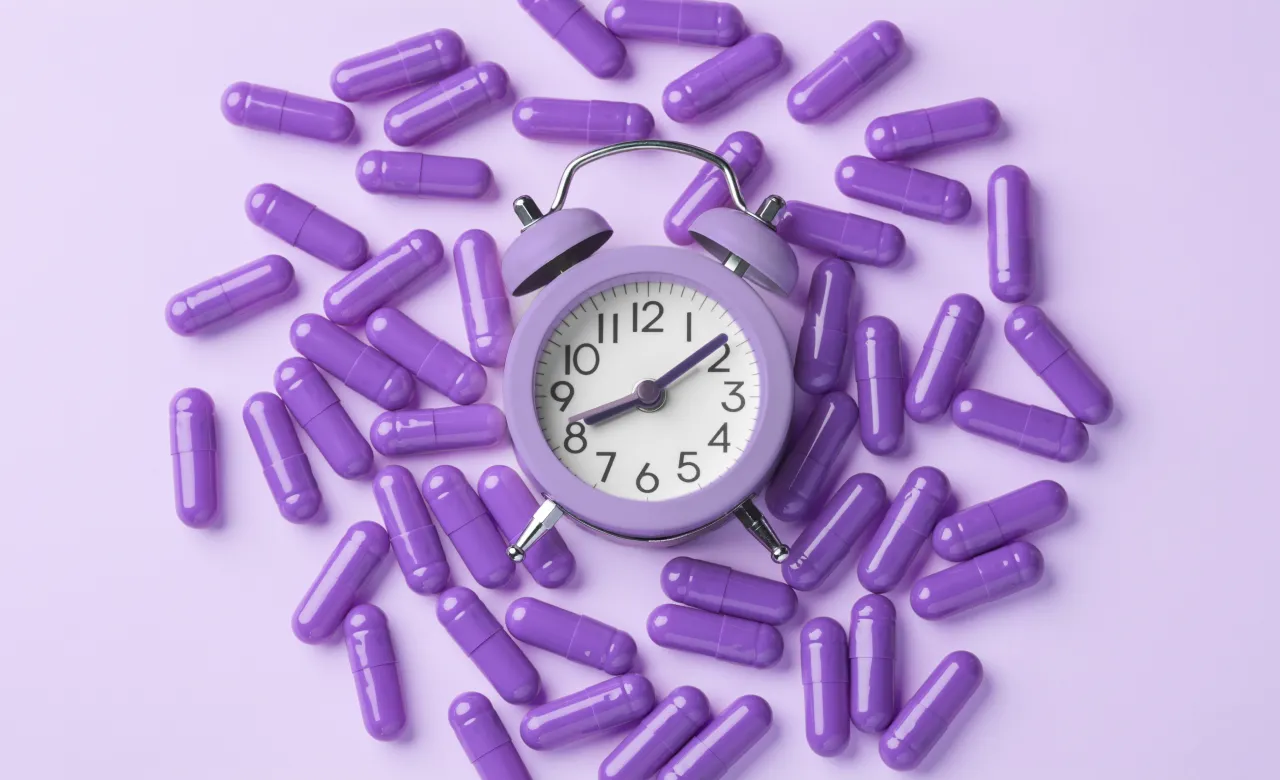 Purple background, purple clock and purple medication in a circle around the clock