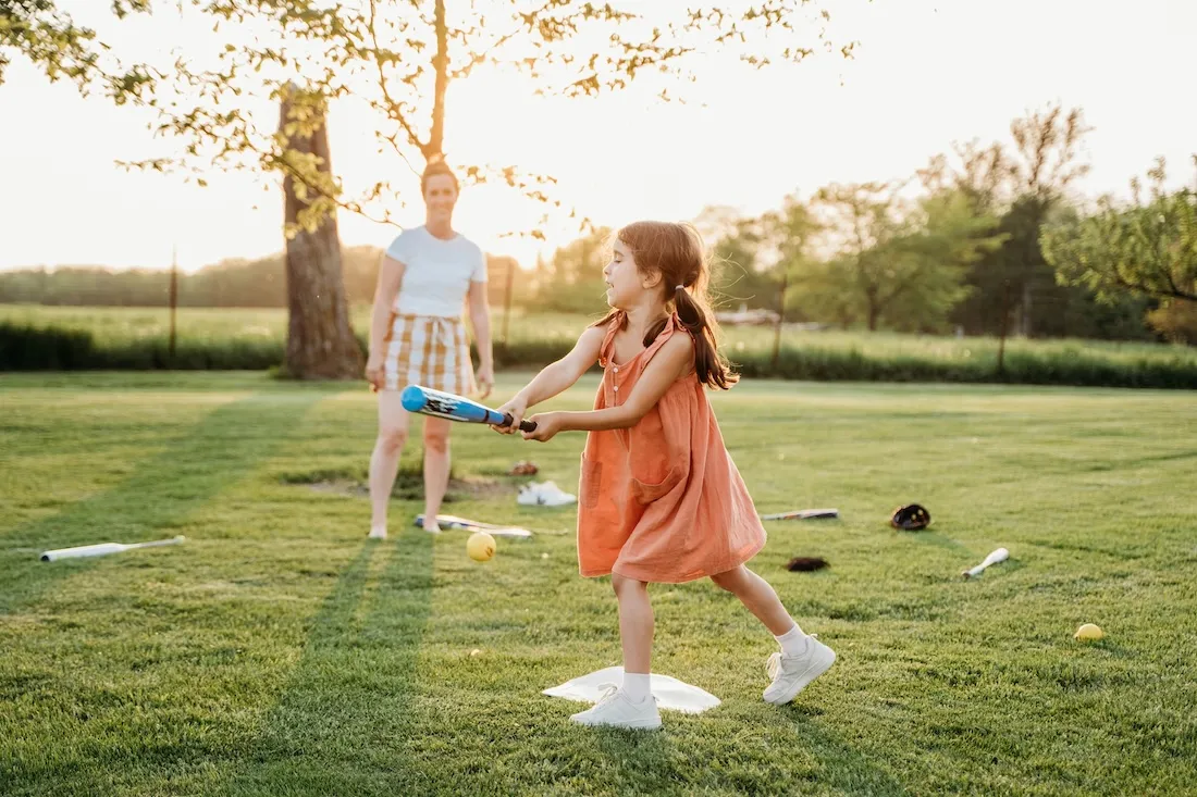Mother and daughter happily playing baseball on a sunny day