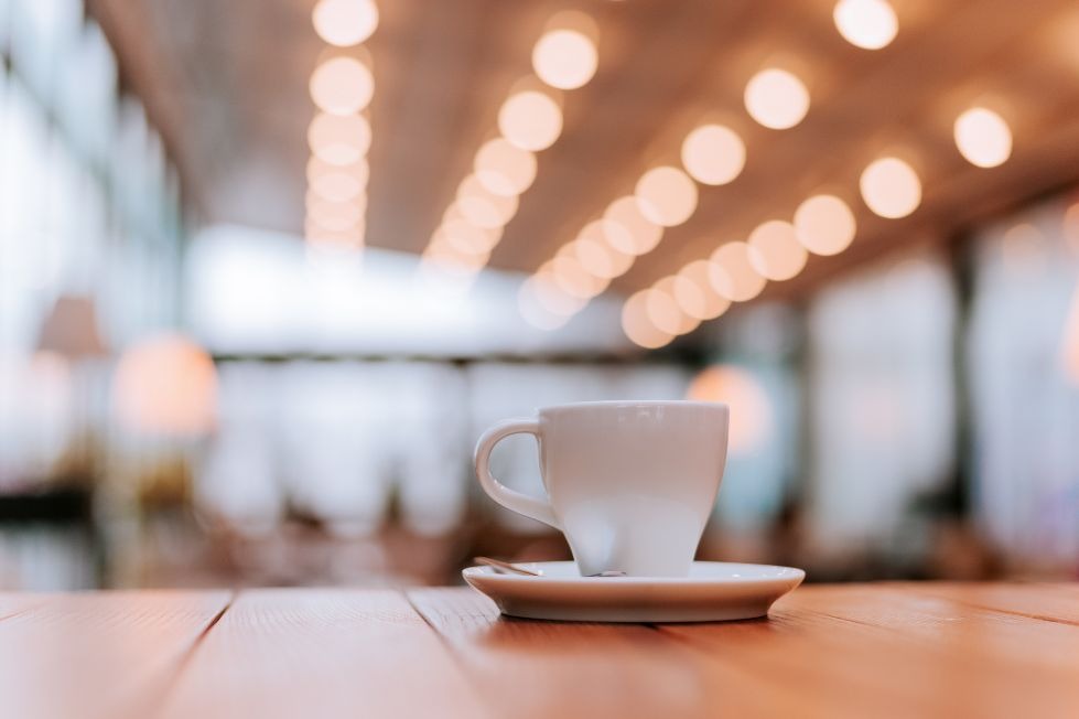 Cup of coffee on a wooden café table, illustrating coffee culture.