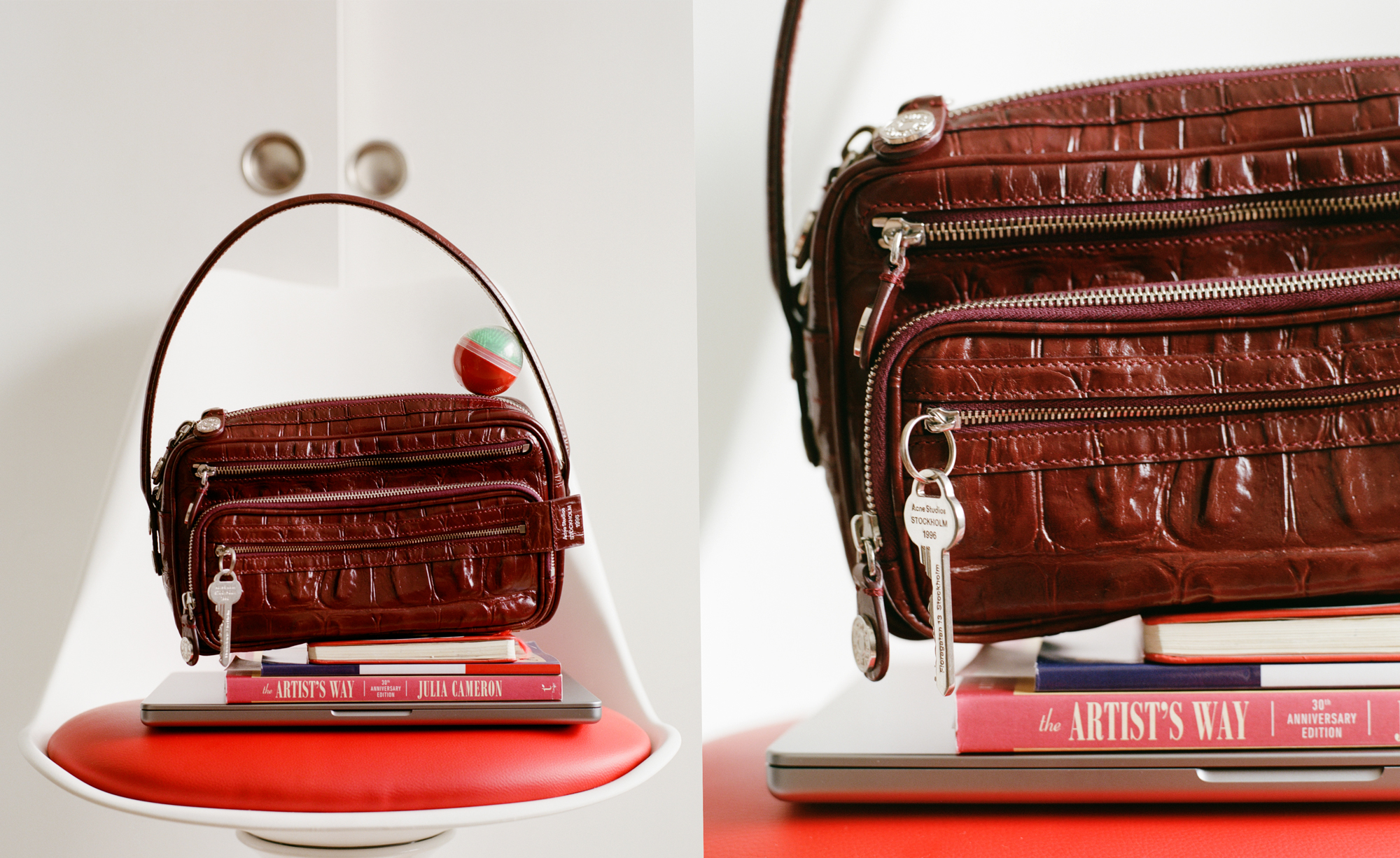 Brown leather handbag with a keychain resting on books and a laptop on a red-cushioned white chair.