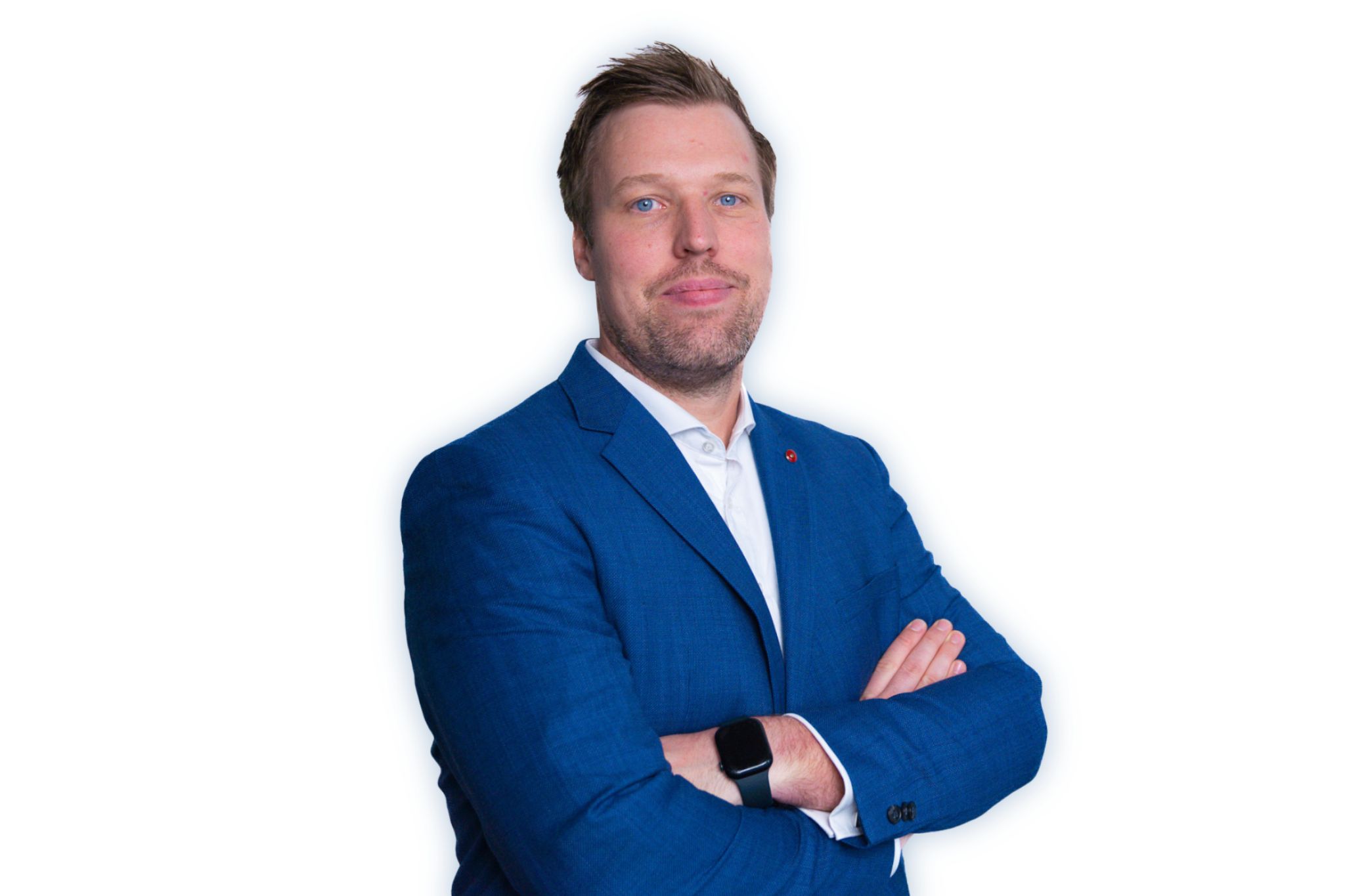 Man with light brown hair and blue eyes wearing a blue suit jacket and white shirt, arms crossed, on white background.