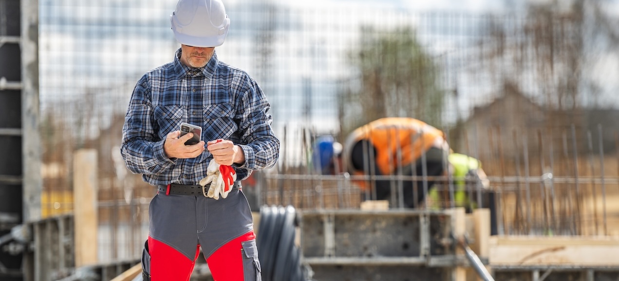 Handwerker nutzt Smartphone auf einer Baustelle für Social Recruiting