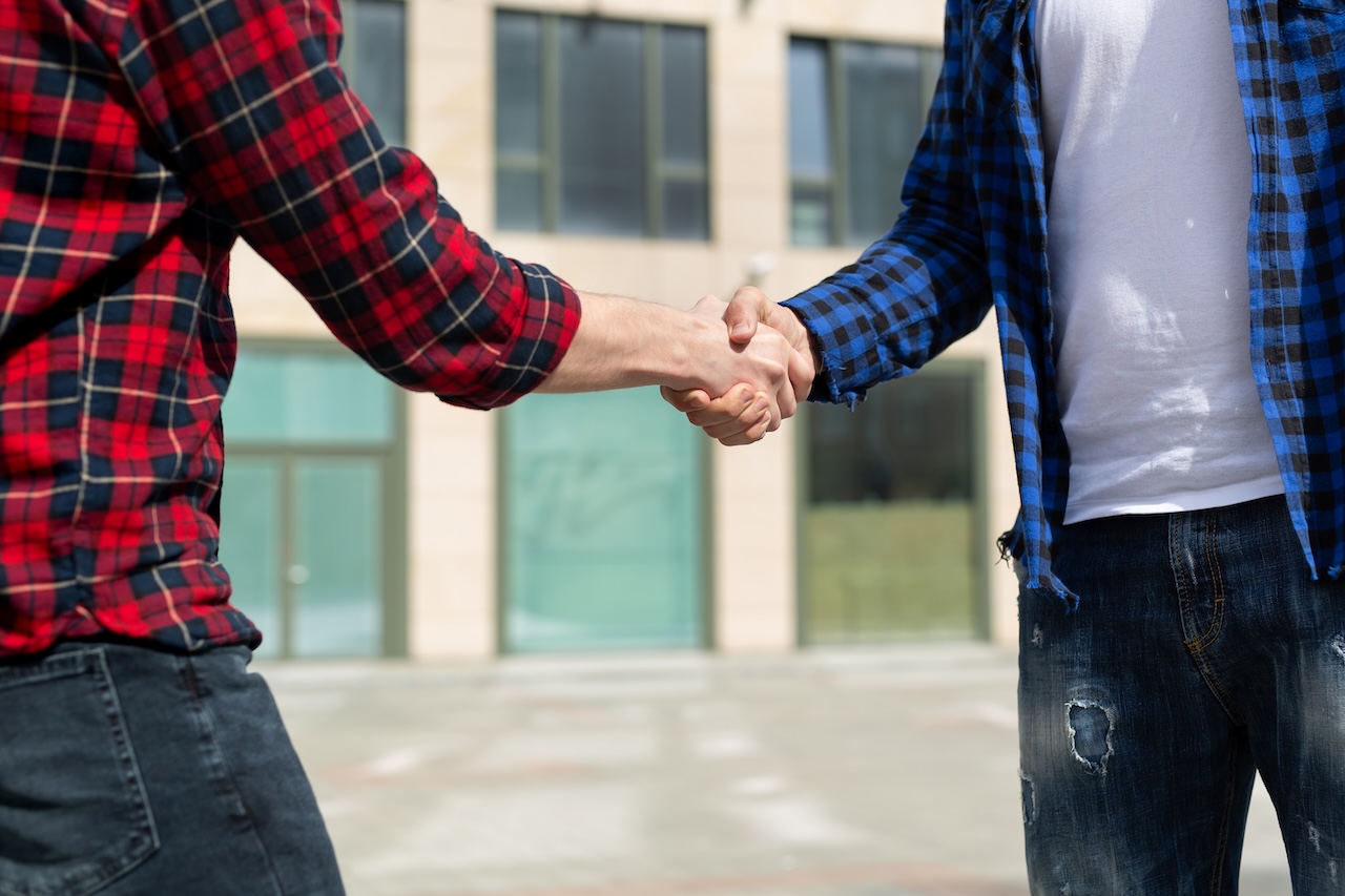 Handschlag zwischen zwei Mitarbeitern in Arbeitskleidung bei einer Einigung