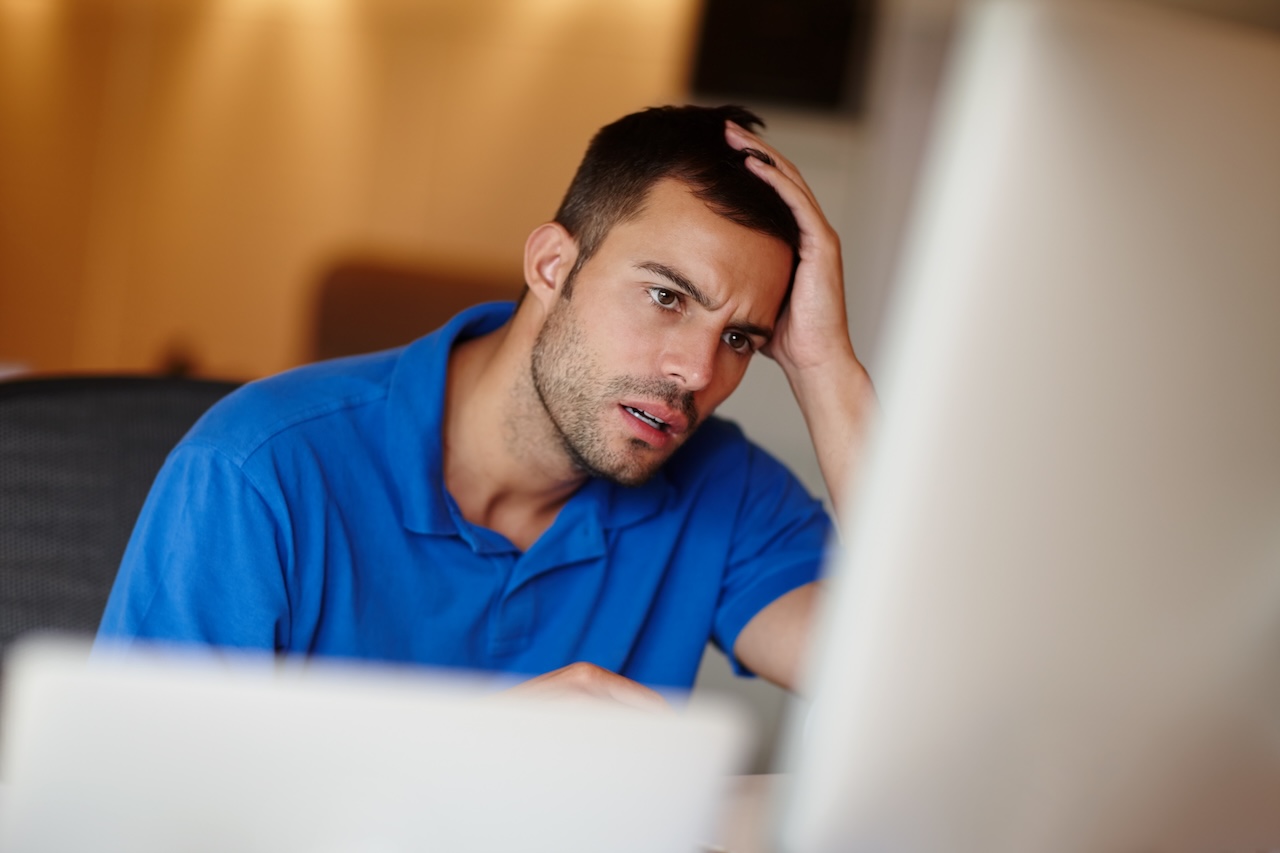 Frustrierter Mann im blauen Poloshirt blickt auf einen Laptop-Bildschirm