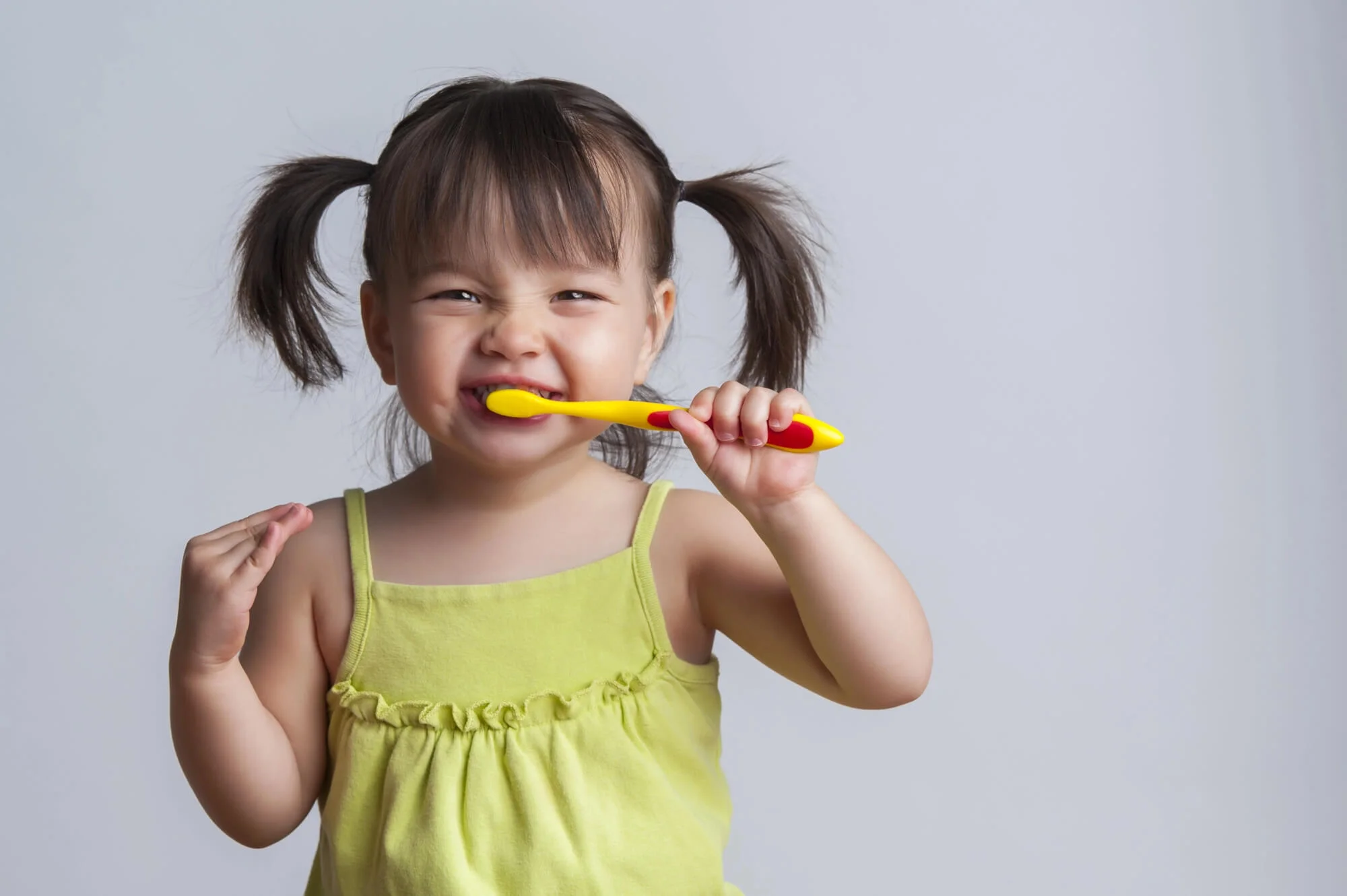 Toddler brushing teeth with yellow toothbrush pediatric dentist in Murfreesboro, TN