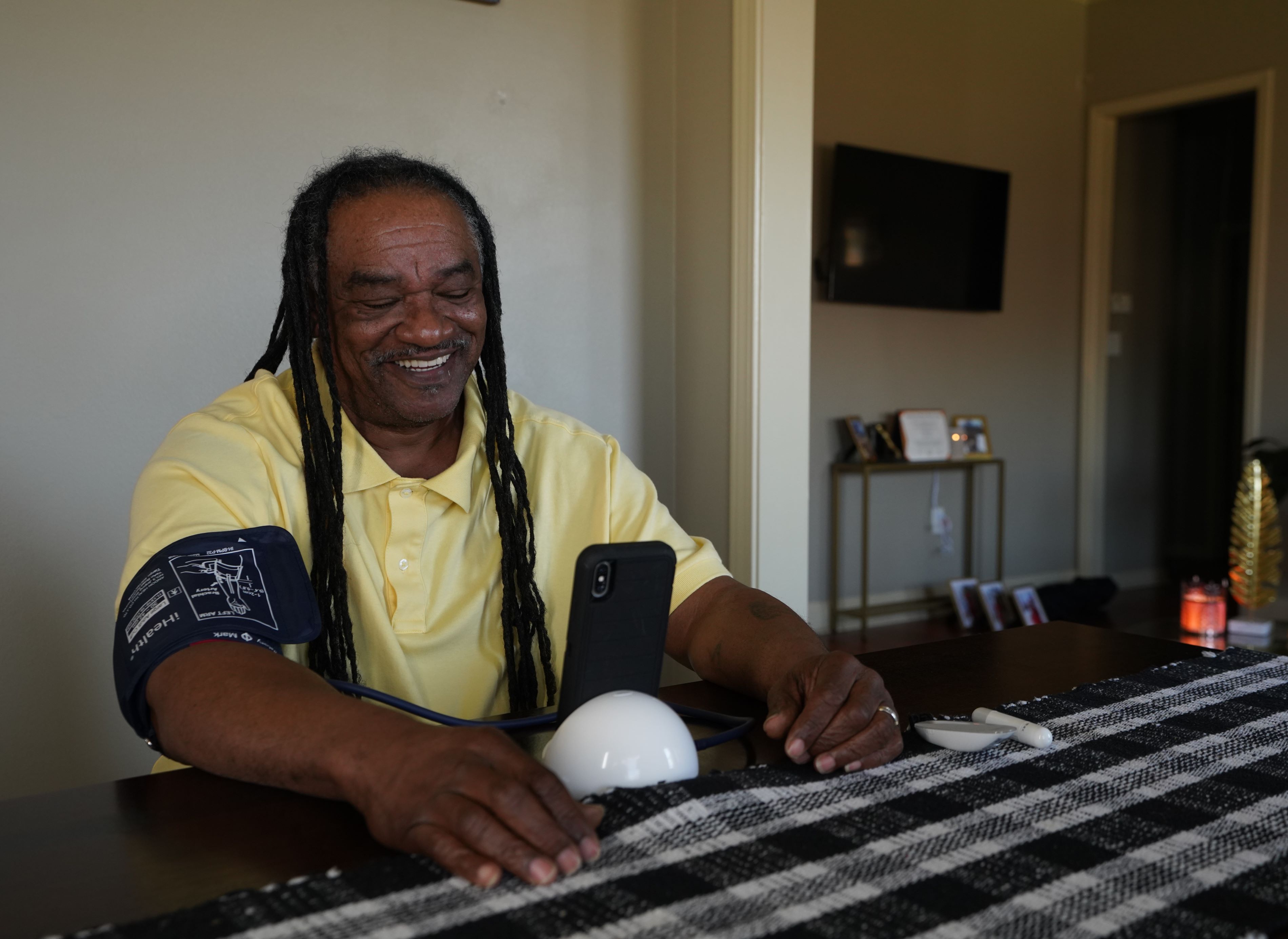 smiling man seated at table taking blood pressure reading
