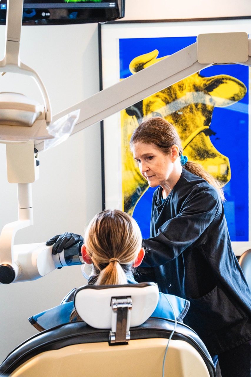 oral exam of patient that is laying down on dental chair with an always there dental care employee taking a x-ray scan