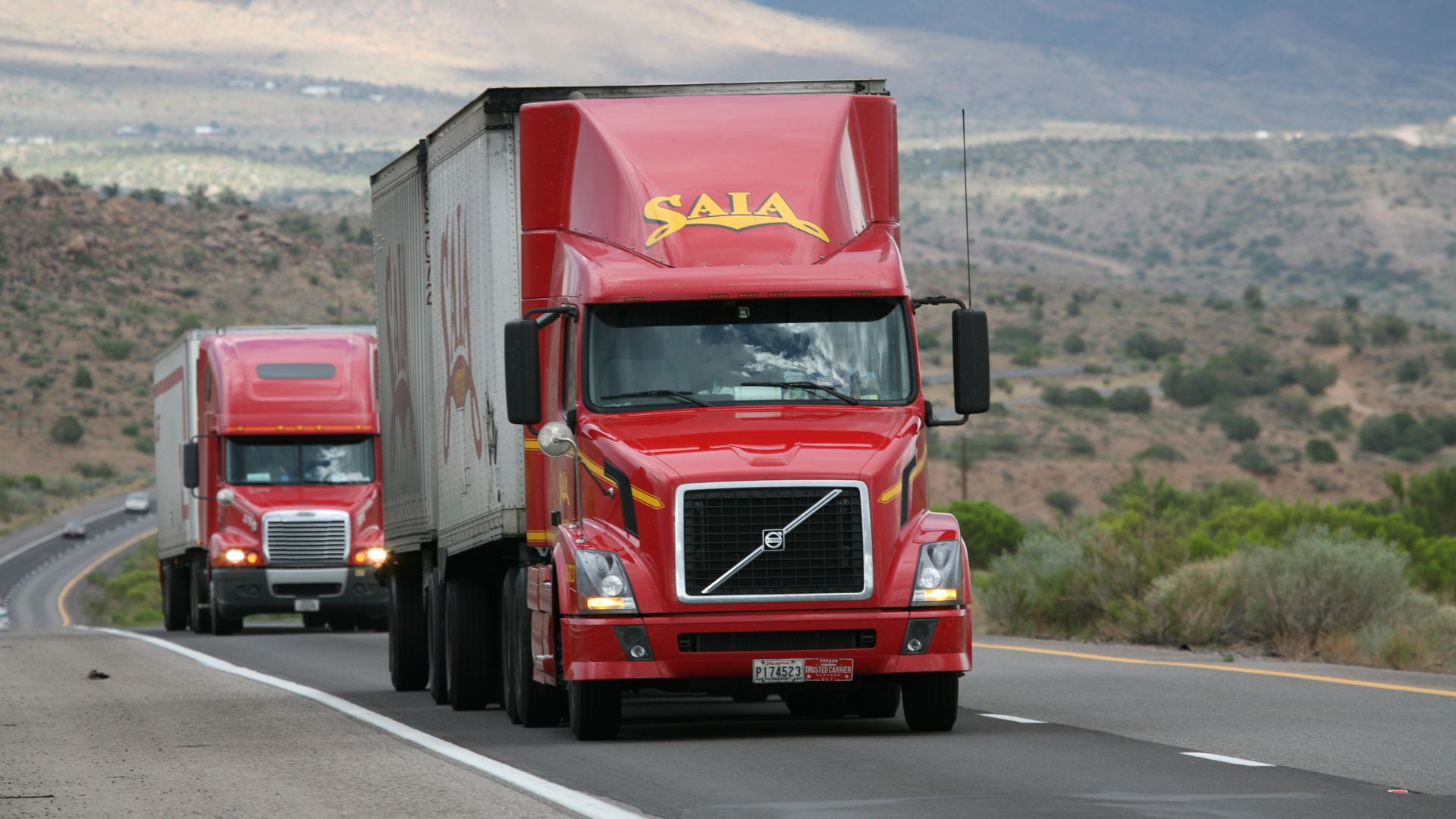 Trucks driving through a scenic Western desert landscape, representing Salt Lake City 3PL shipping reach
