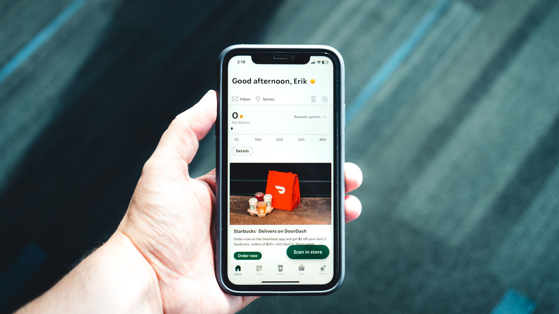 Hand holding a smartphone showing a shopping and delivery app