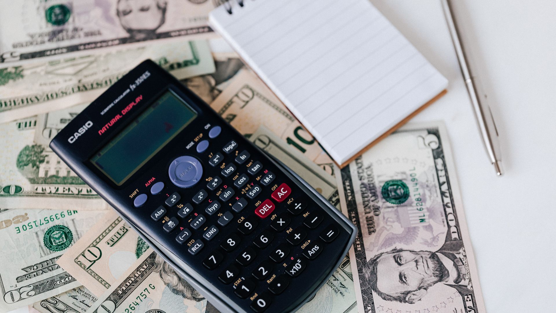Calculator and notepad on a stack of dollars representing 3PL fulfillment cost analysis