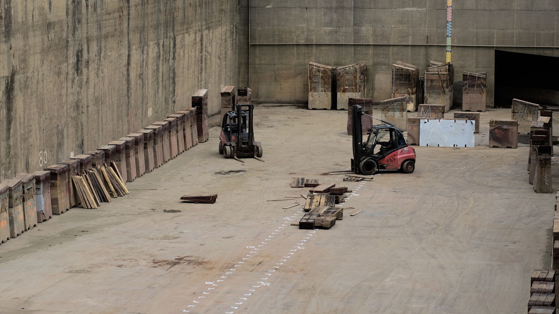 Forklifts and stacked pallets inside a large industrial warehouse