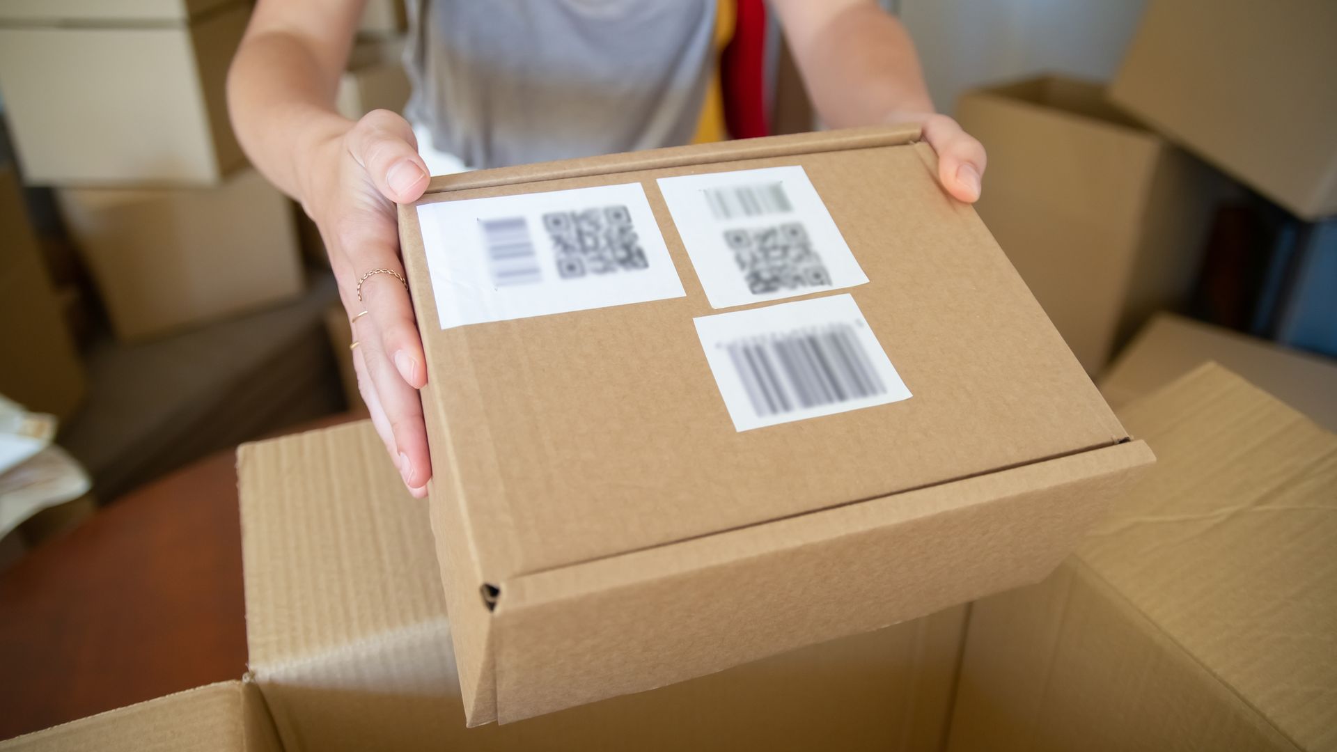 Close-up of a person applying a barcode label to a cardboard box before shipping