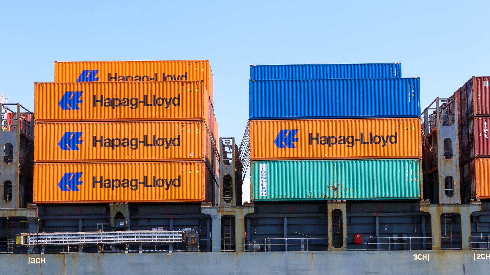 Stacked shipping containers at an industrial port terminal, representing landed cost for imported inventory