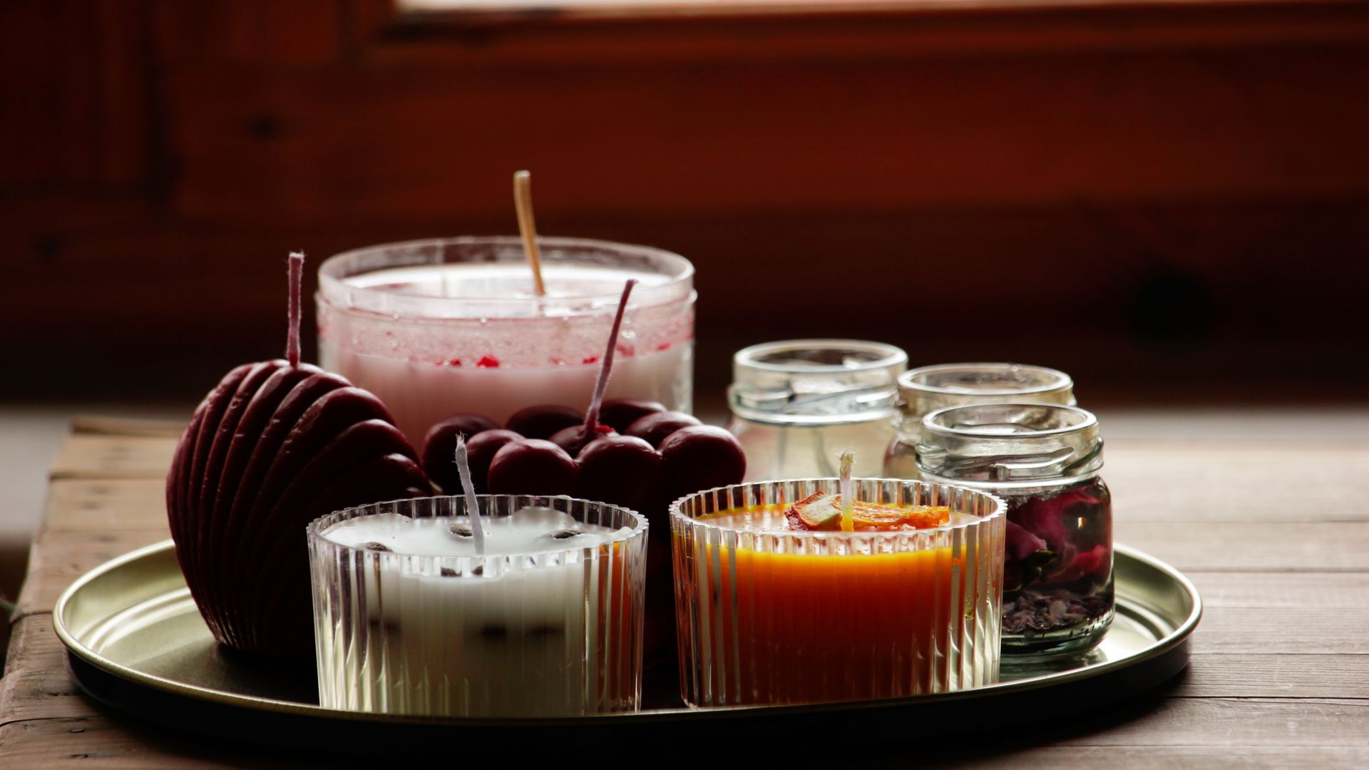 An assortment of scented candles in glass jars arranged on a surface