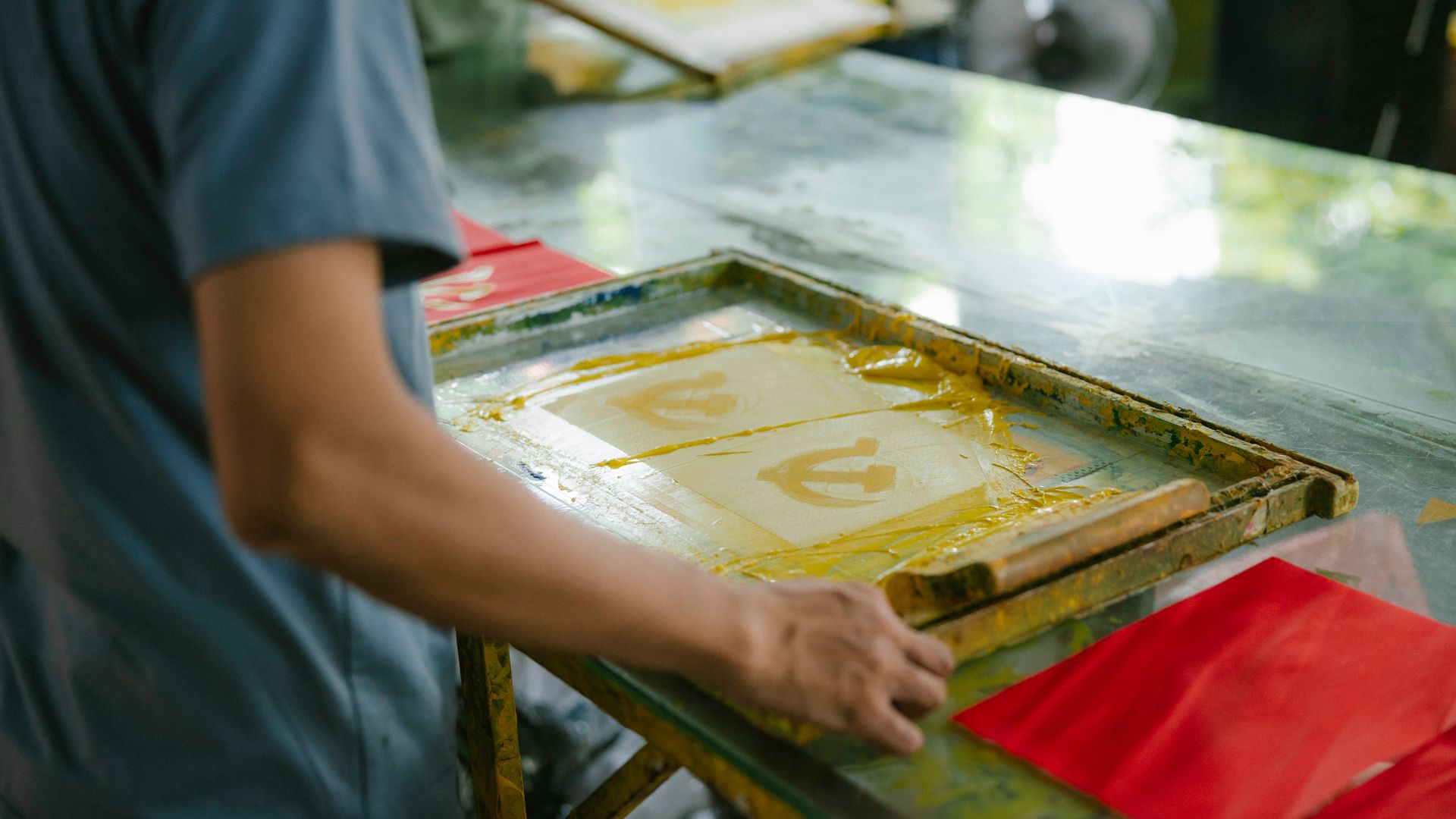 A worker operating a screen printing machine in a print shop